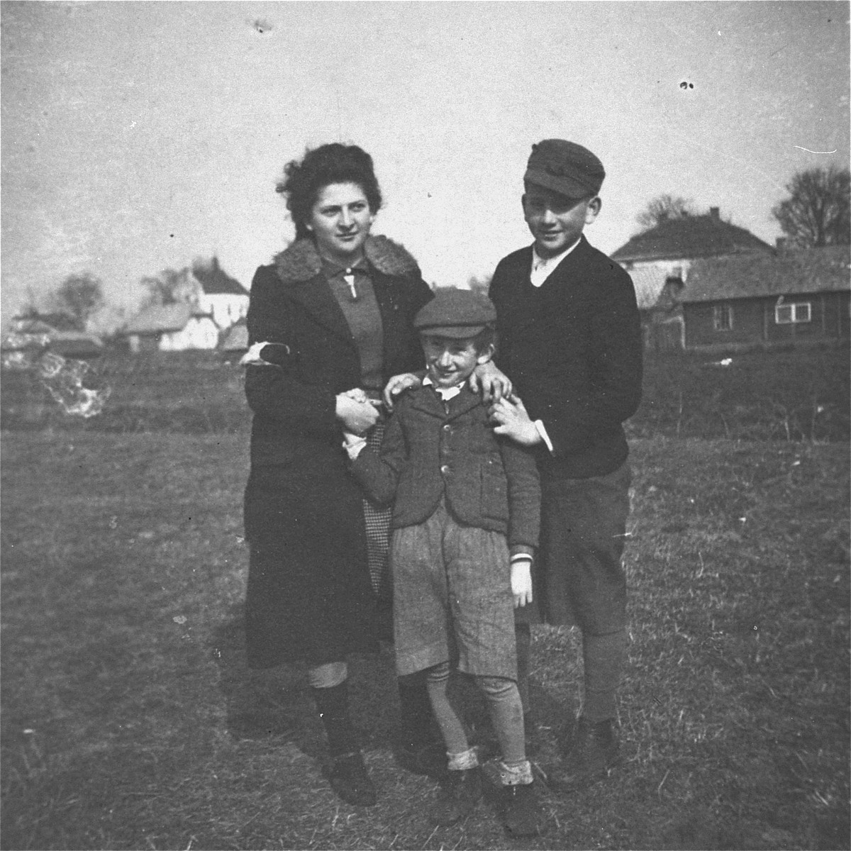 Three Jewish siblings pose outside in the Kolbuszowa ghetto.

Pictured are Manius, Leon and Niunia Notowicz.
