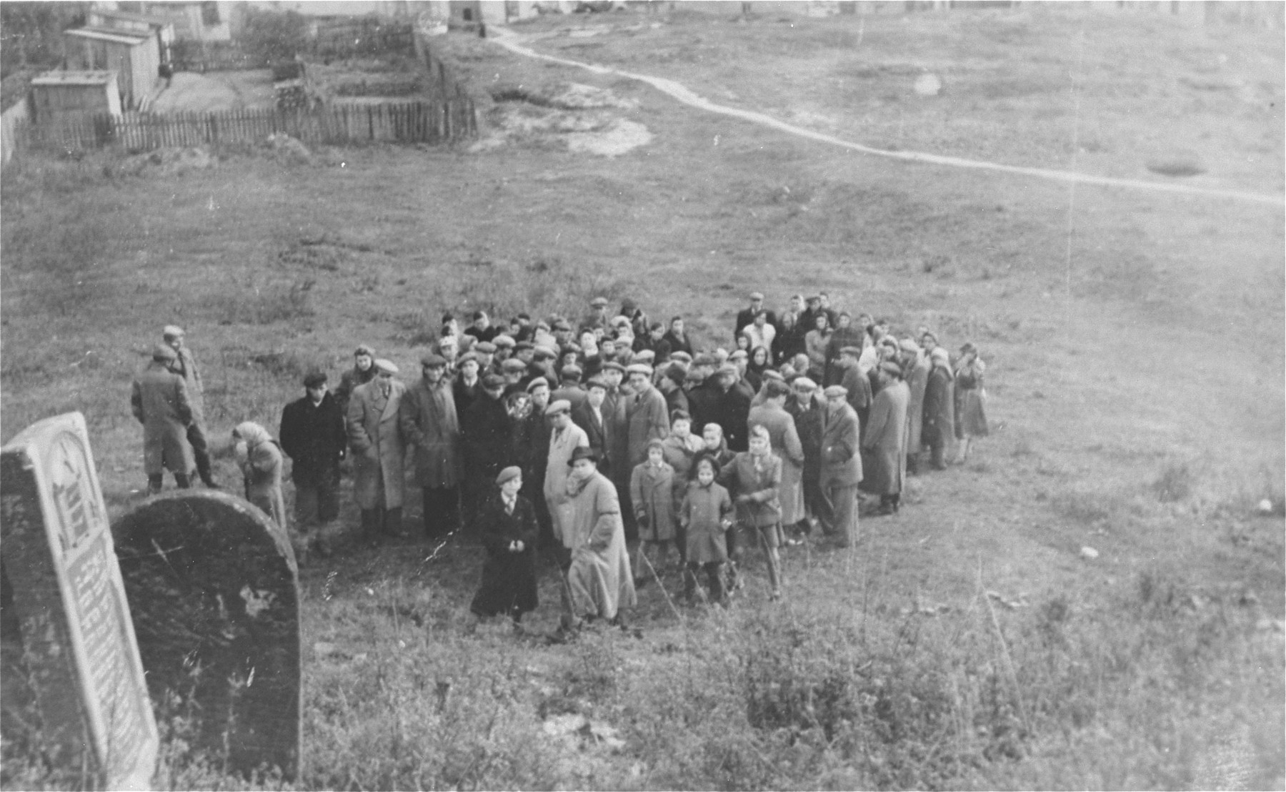 Survivors from Ostrowiec walk toward the site of a mass grave for 2000 Jews shot during the October 1942 action.  

In the foreground is a portion of the vandalized Jewish cemetery.