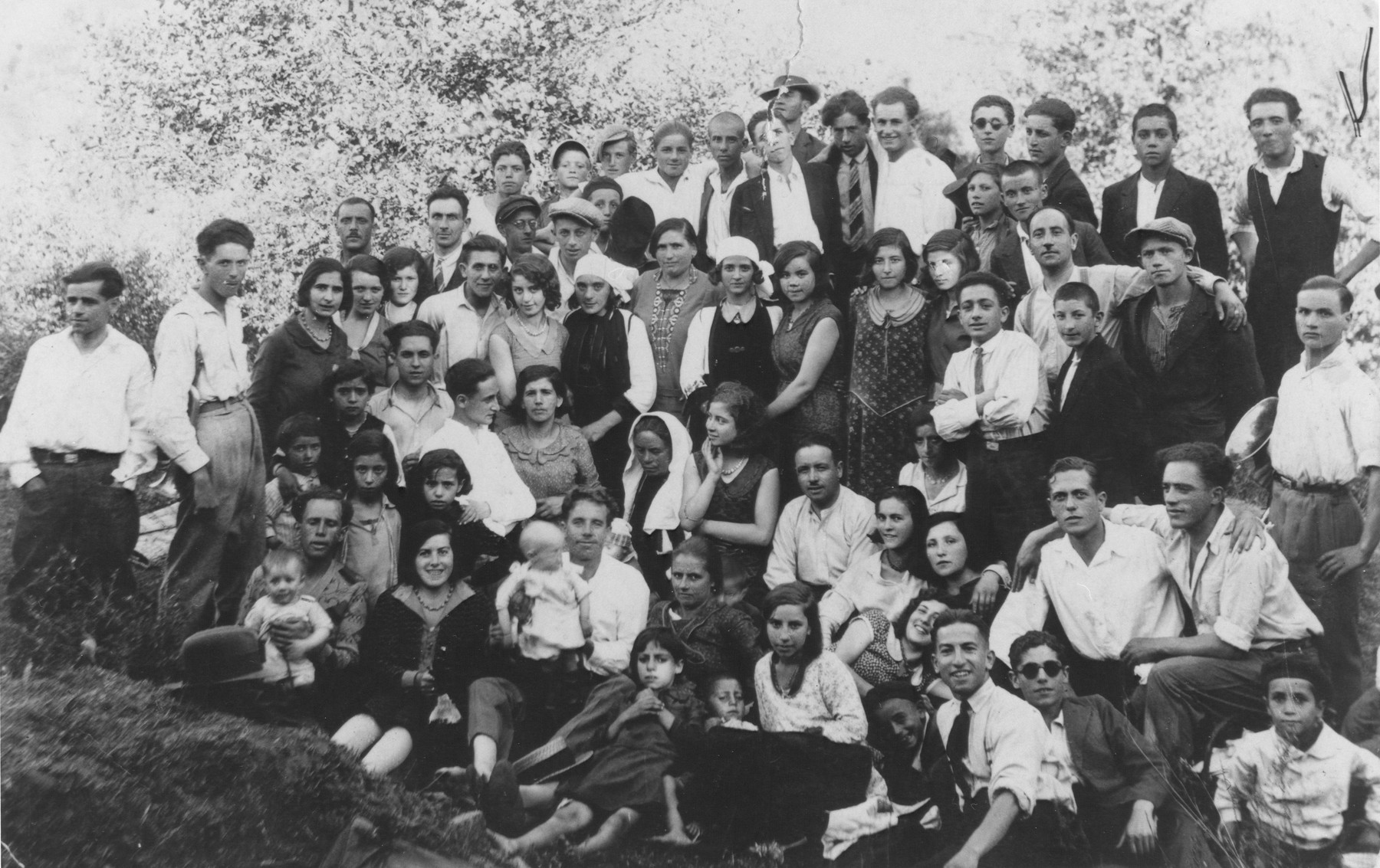 A large group of  young Jewish men and women pose outdoors near a woods in Bitola.