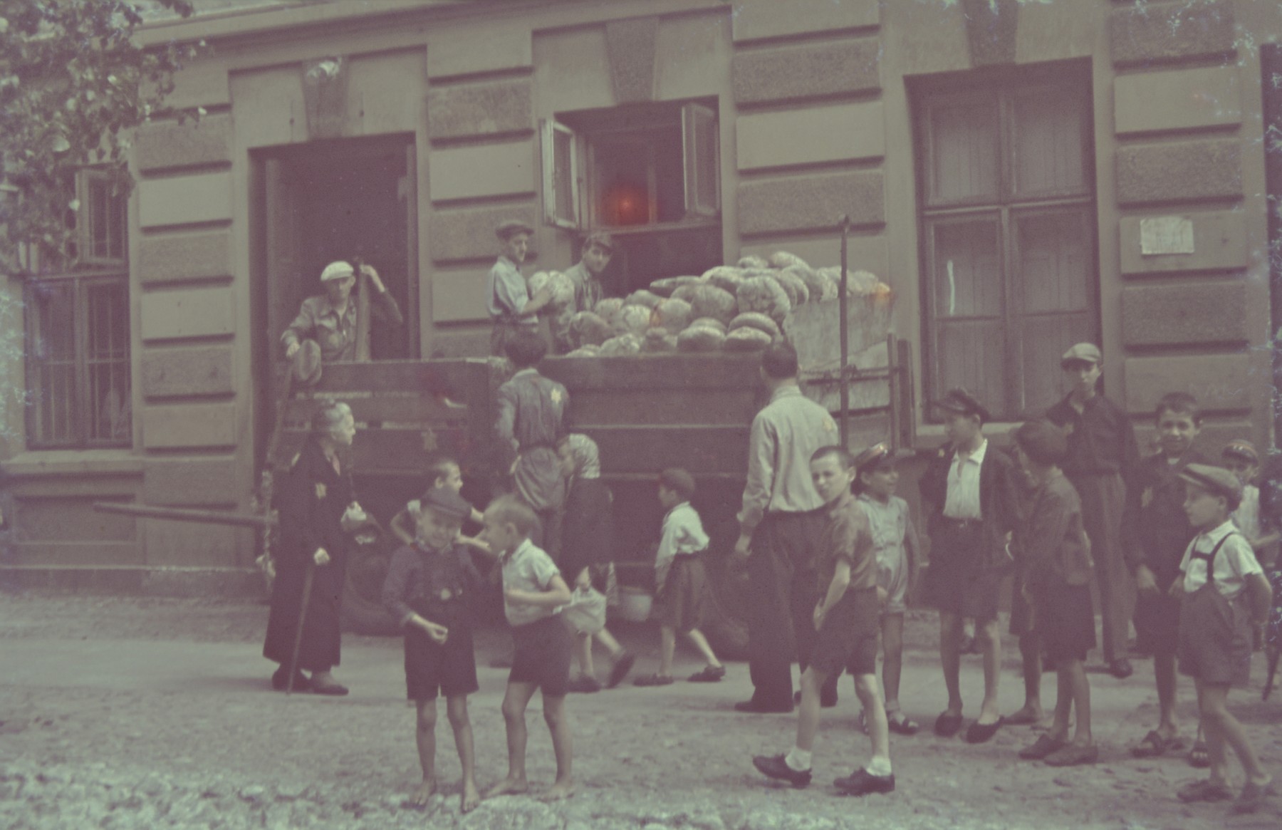 Children wait outside the bread distribution center in the Lodz ghetto.

Original German caption: "Strassenbild" (street scene), #147.
