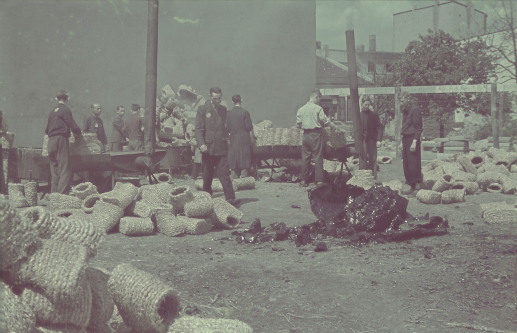 Workers sort coils of straw in the factory for straw shoes of the Lodz ghetto.

Original German caption: "Getto-Litzmannstadt, Strohschuhfabrik" (straw shoe factory), #206 [number partially obscured]