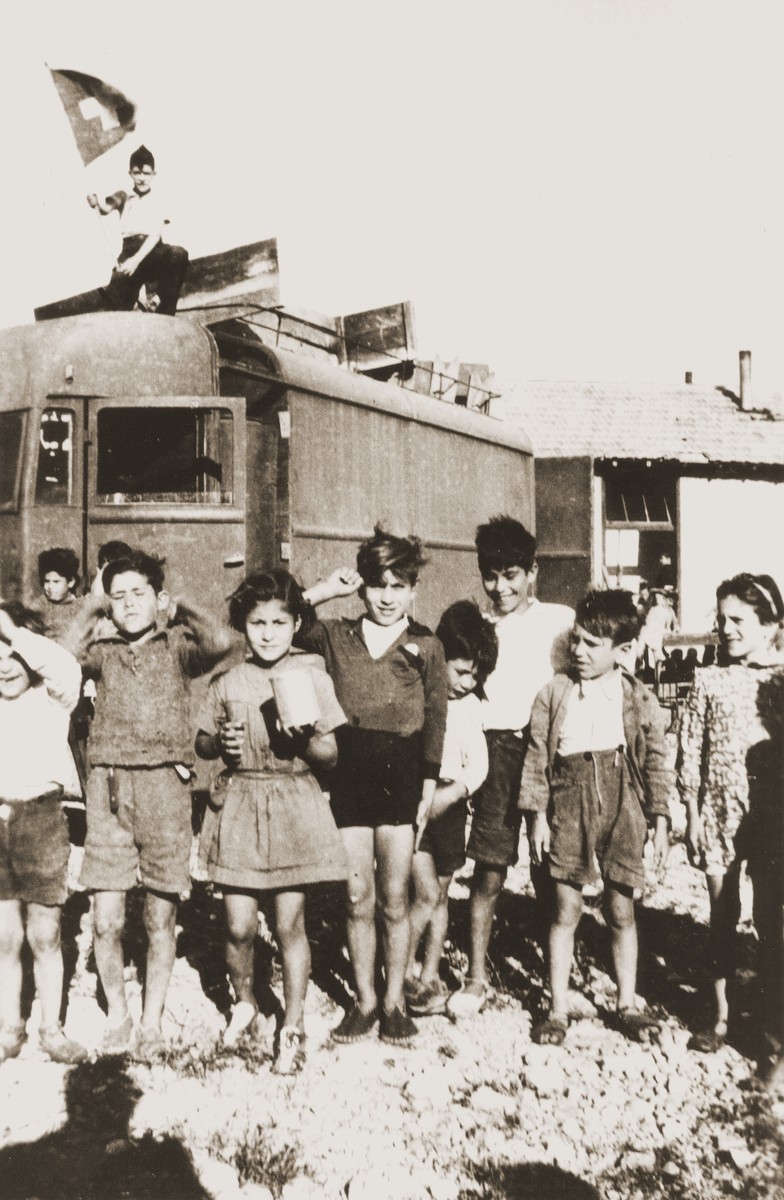 Children in Rivesaltes pose beneath a Swiss flag on the occasion of the Secours Suisse moving its quarters in the camp.