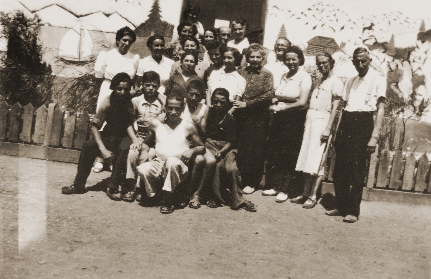 Group portrait of relief workers standing in front of the Secours Suisse building which is decorated with a mural of the Swiss Alps.