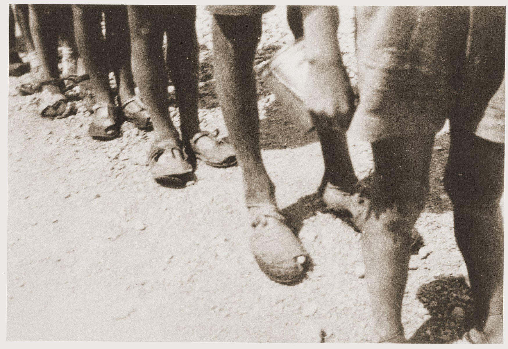 Children stand in line to exchange their old shoes for new ones at the Rivesaltes internment camp.