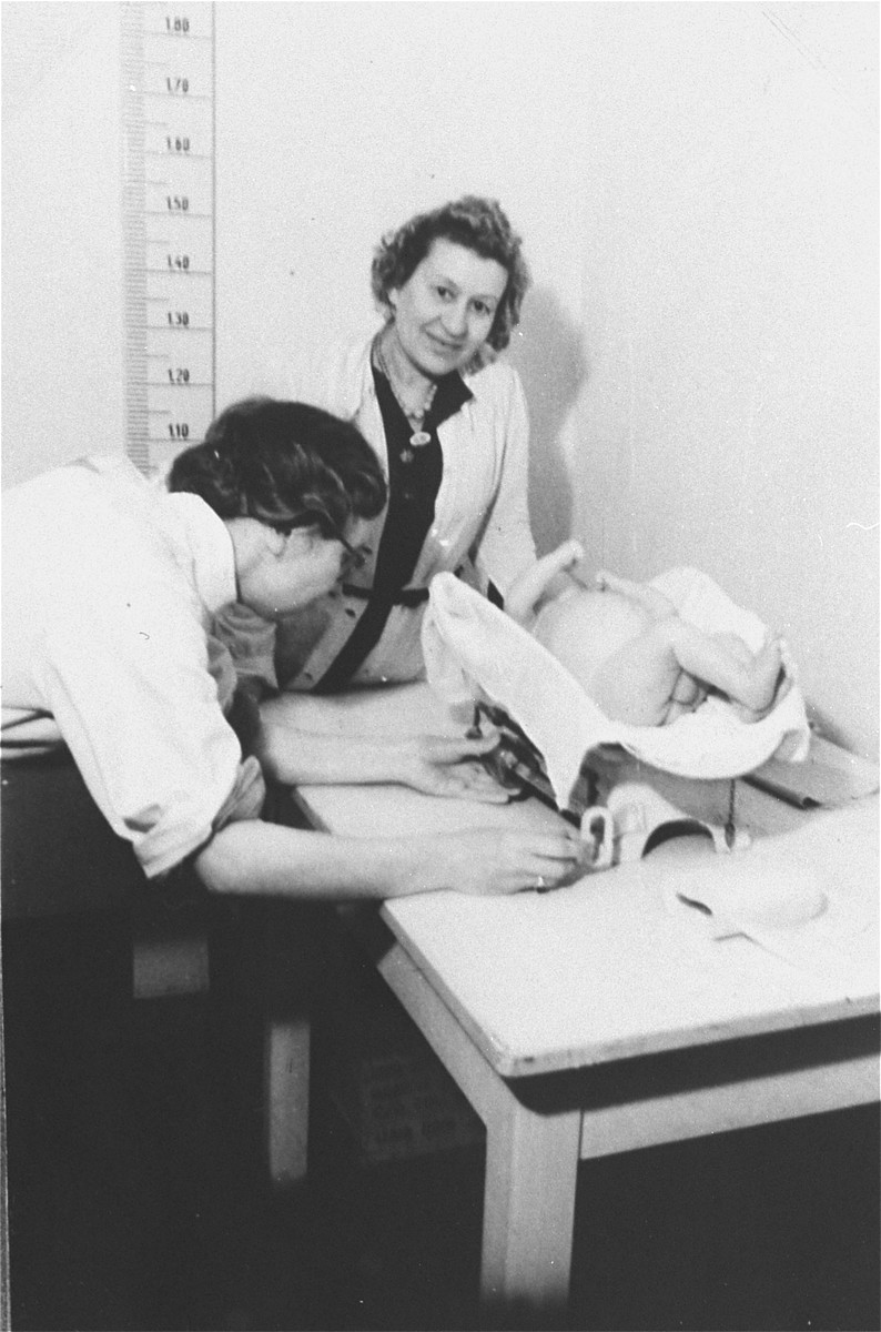 A nurse weighs and measures a young infant in the Zeilsheim displaced person's camp hospital.