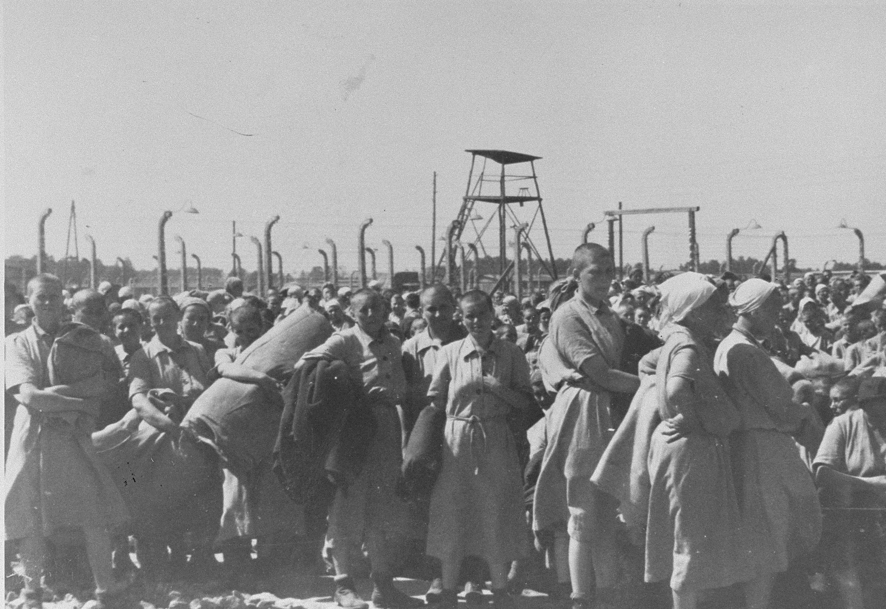 Jewish women from Subcarpathian Rus who have been selected for forced labor at Auschwitz-Birkenau, march toward their barracks after disinfection and headshaving.