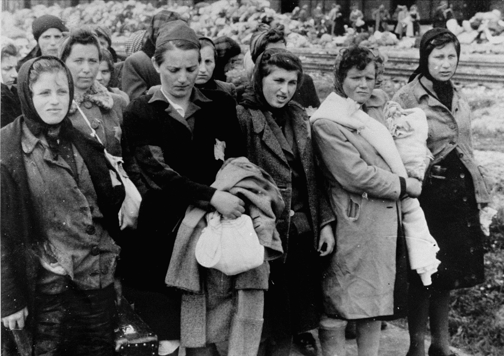 Jewish women from Subcarpathian Rus who have been selected for forced labor at Auschwitz-Birkenau, wait to be taken to another section of the camp.