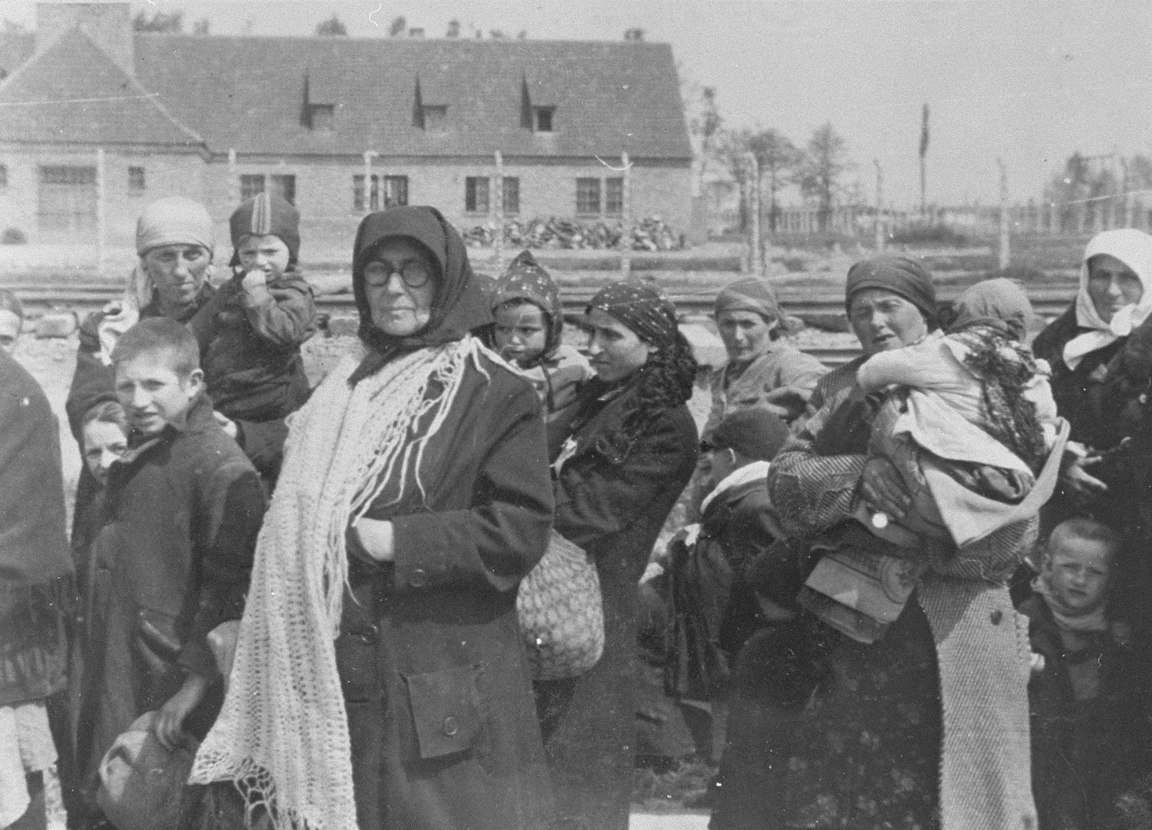 Jewish women and children from Subcarpathian Rus who have been selected for death at Auschwitz-Birkenau, walk toward the gas chambers.

The building in the background is crematorium III. 

Those pictured include Iboja Hoffman of Bodrogkeresztur, her aunt Lena Egri, Ruth Hoffman (Iboja's sister), Malwin Hoffman (Iboja and Ruth's mother), Piroska Szaz of Tokaj (Lena and Malwin's sister), Piroska's daughter and Karcsi Szaz (Piroska's son).
