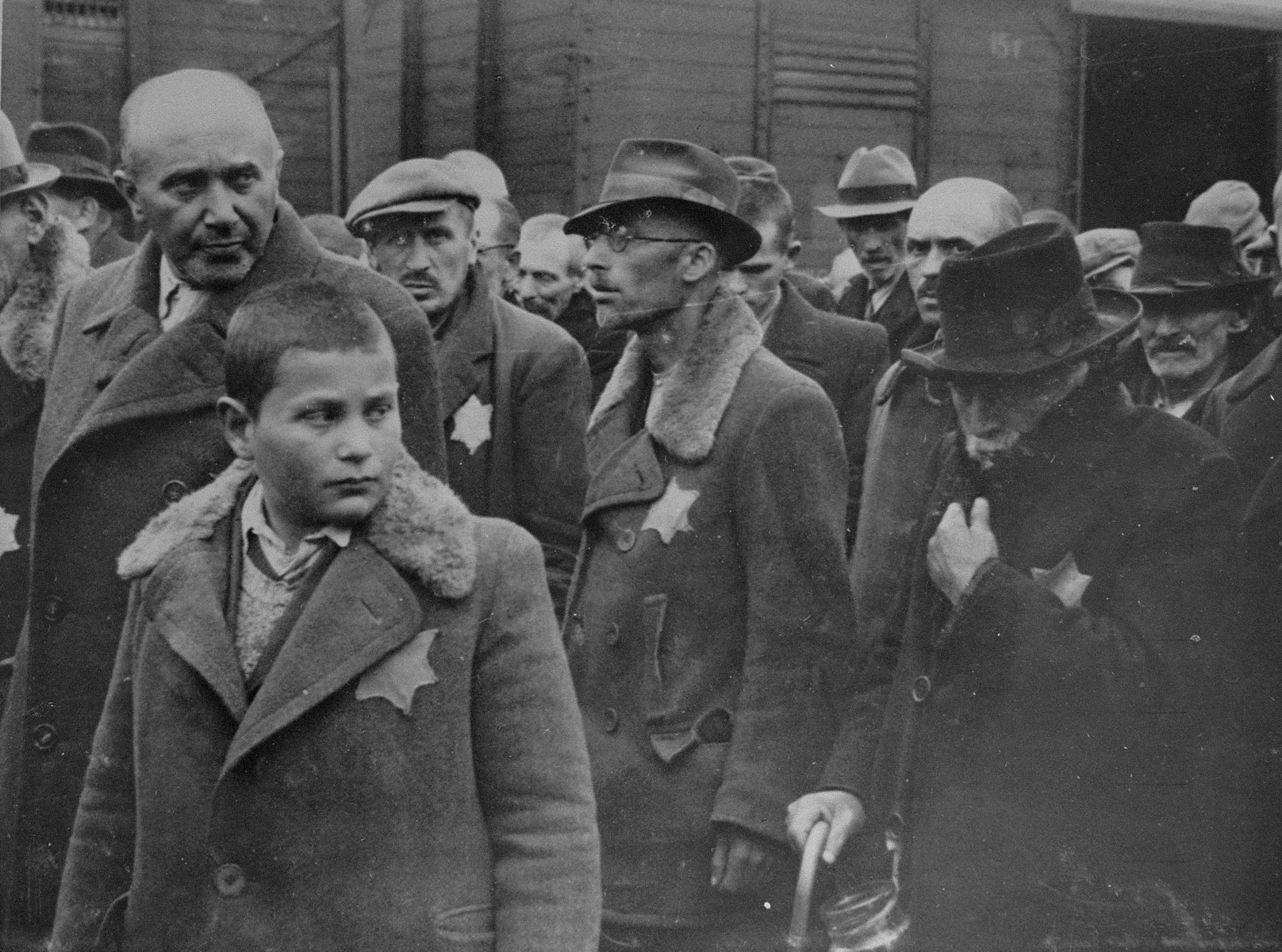 Jewish men and boys from Subcarpathian Rus await selection on the ramp at Auschwitz-Birkenau.

The man in the center wearing glasses is Sigmund Bruck, a mechanical engineer from Tab.  Bruck was denounced as a communist, arrested and deported to Nagy Kamizsa.  He was eventually sent to Auschwitz-Birkenau and then to Gleiwitz, where he was killed by a guard during an escape attempt.  To his left is Mr. Smilazick and his son.