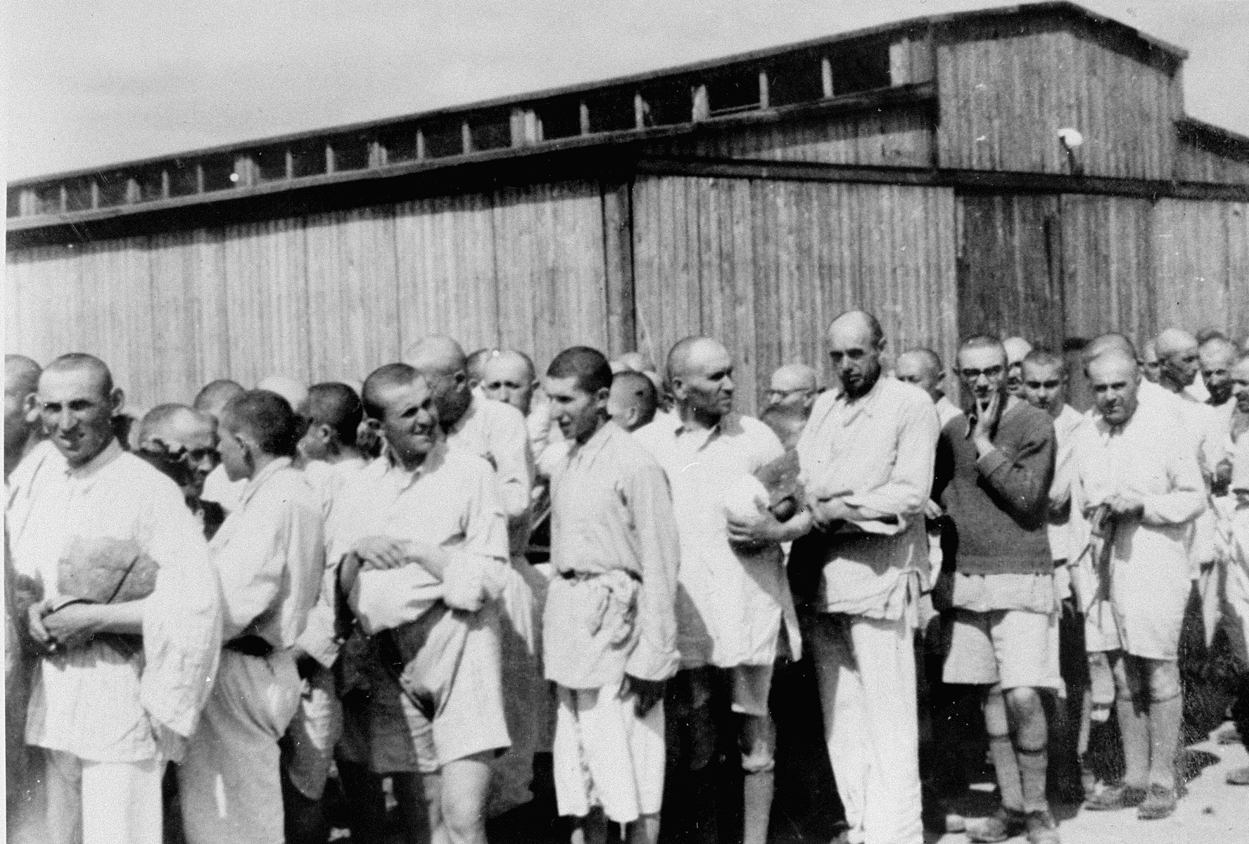 Jewish men from Subcarpathian Rus who have been, selected for forced labor at Auschwitz-Birkenau, await further processing after having been disinfected and issued underclothing. 

Those pictured include Zoltan Hoffman and his son Herschel.