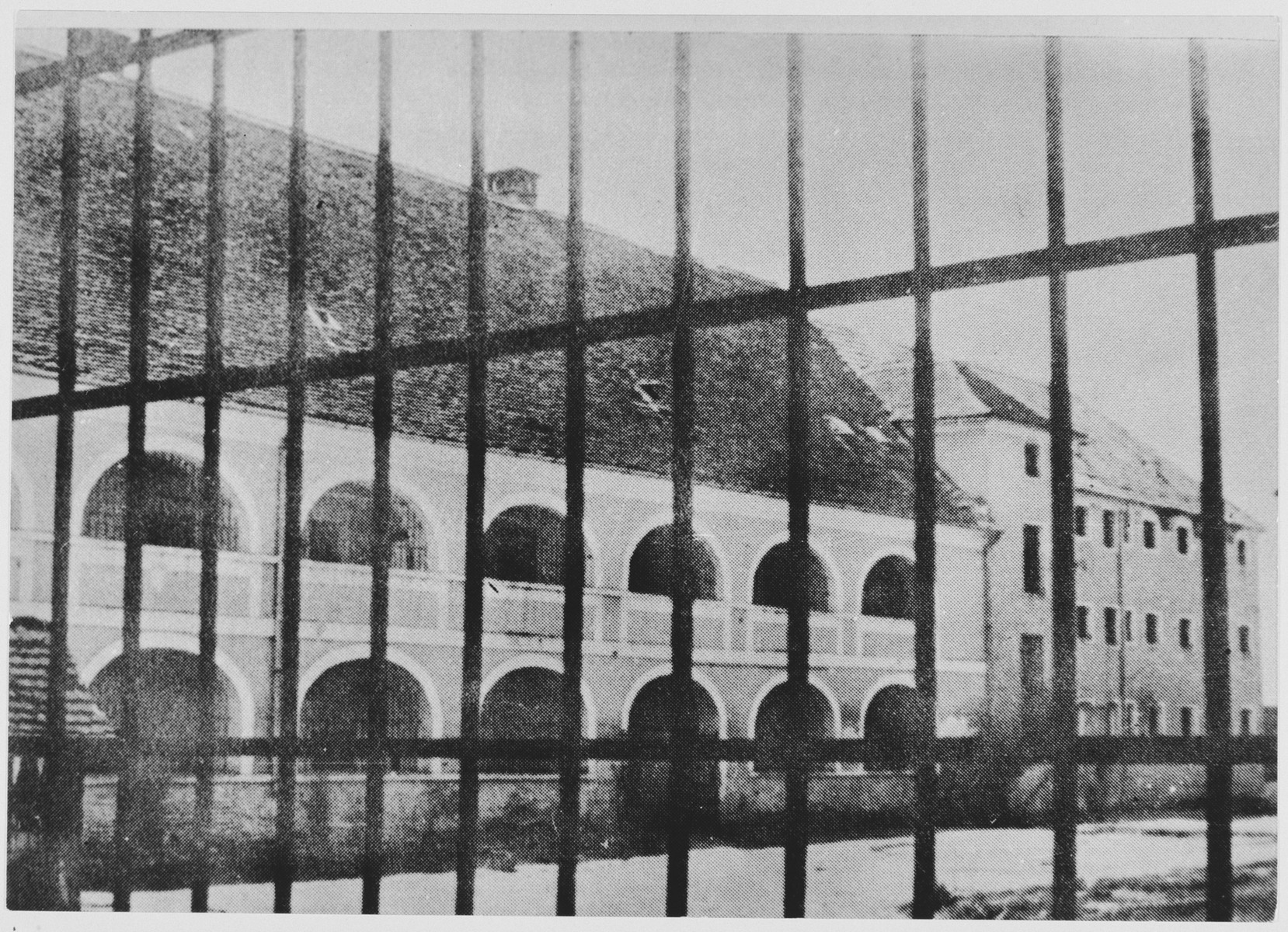 View through a tall fence of prisoner barracks in the men's camp at the Stara Gradiska concentration camp.

At the left are quarters for Jewish and Serbian inmates; at the right, for Croats, Muslims and Catholics.