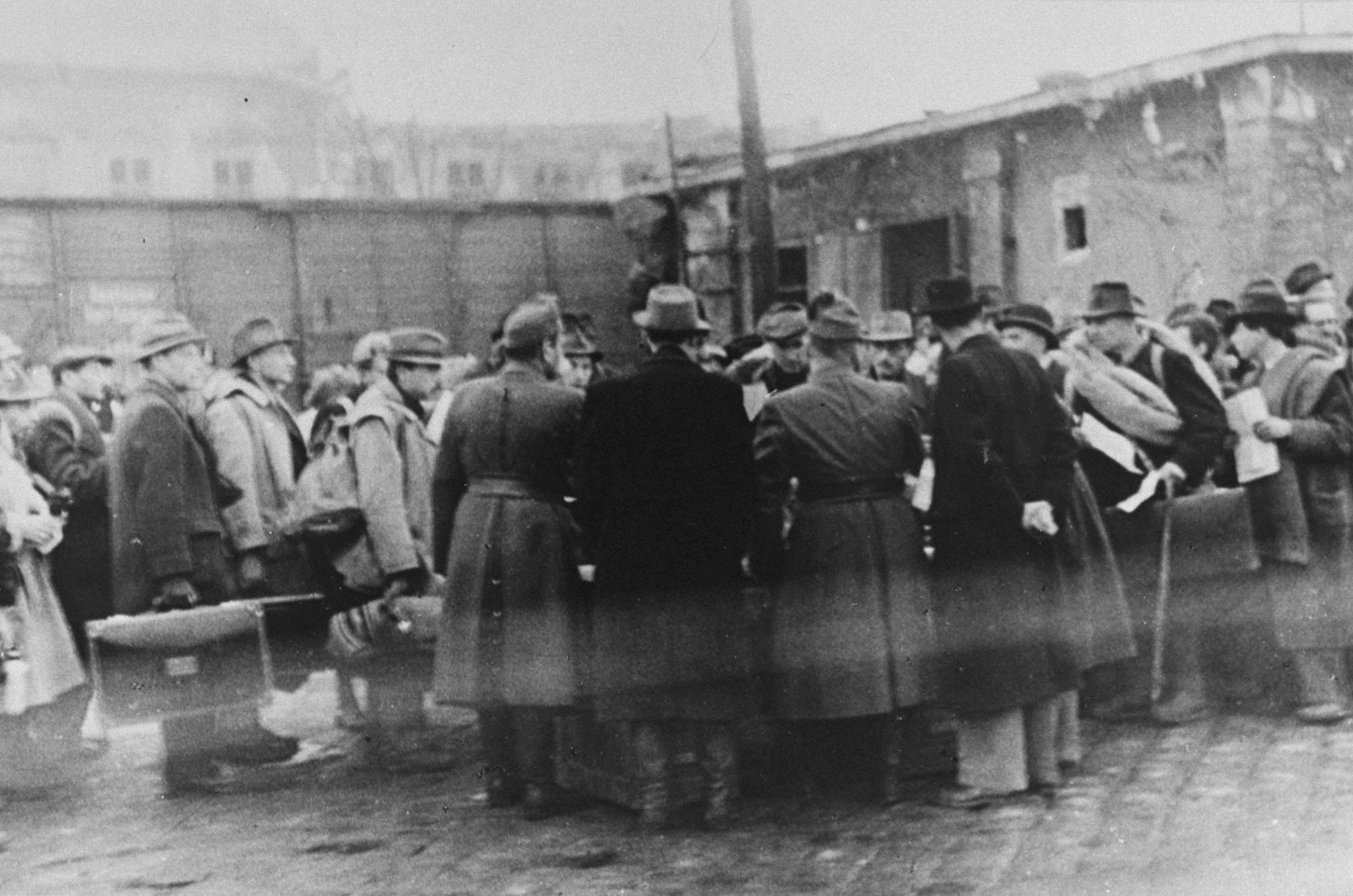 Raoul Wallenberg is present at the Jozsefvaros train station in Budapest where Jews who have been rounded-up for deportation, wait on the platform.

Wallenberg stands on the right with his hands clasped behing his back.  On one side of him is an officer of the Hungarian gendarmie named Lullay; on the other side is a Jew holding a Swedish Schutzpass [protective pass].