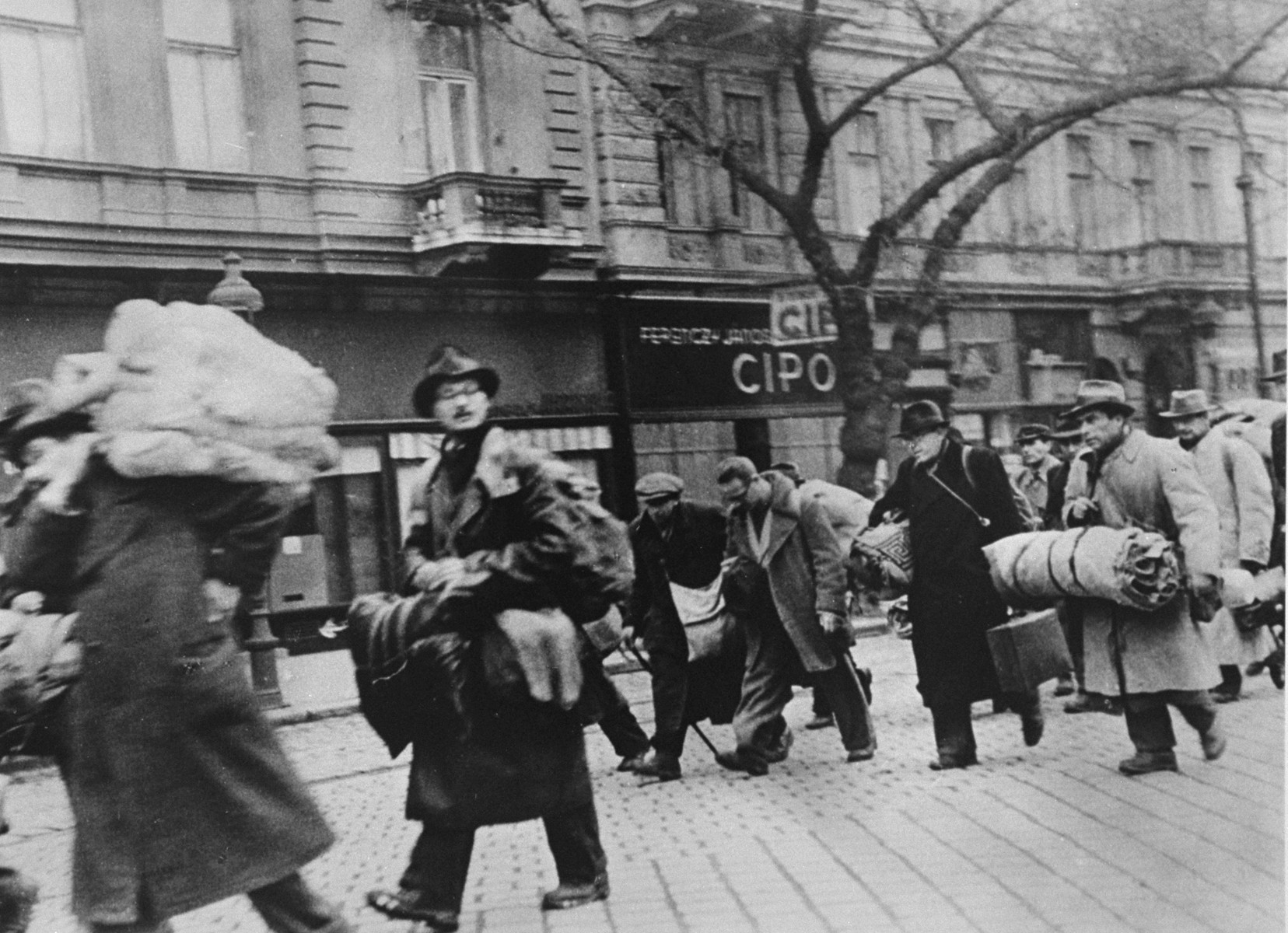 Hungarian Jews who were rescued from deportation by Raoul Wallenberg at the railroad station in the Józsefváros [Jozsefstadt] on November 28, 1944, walk along a street in Budapest on their way back to the "international ghetto". This photo was taken by Thomas Veres from Wallenberg's car as they drove past the group.