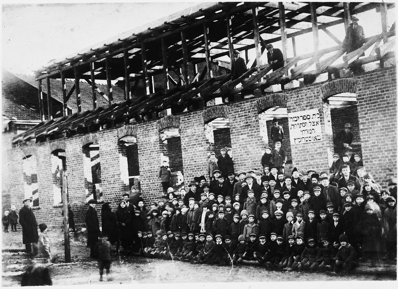 Group portrait of students, teachers and benefactors at the dedication of the new Mizrachi school (that was still under construction) in Ostrowiec, Poland.

Among those pictured is Alte Kesenbaum (an uncle of the donor), who was one of the school's founders.