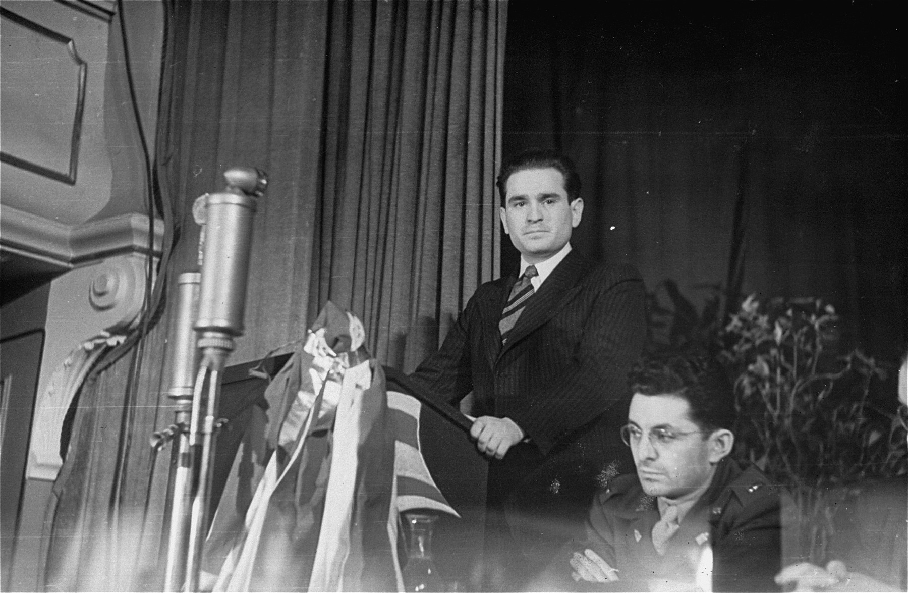Leon Retter addresses a conference sponsored by the Central Committee of Liberated Jews in the U.S. Zone of Germany.  

Seated next to him is U.S. Army chaplain Abraham Klausner.