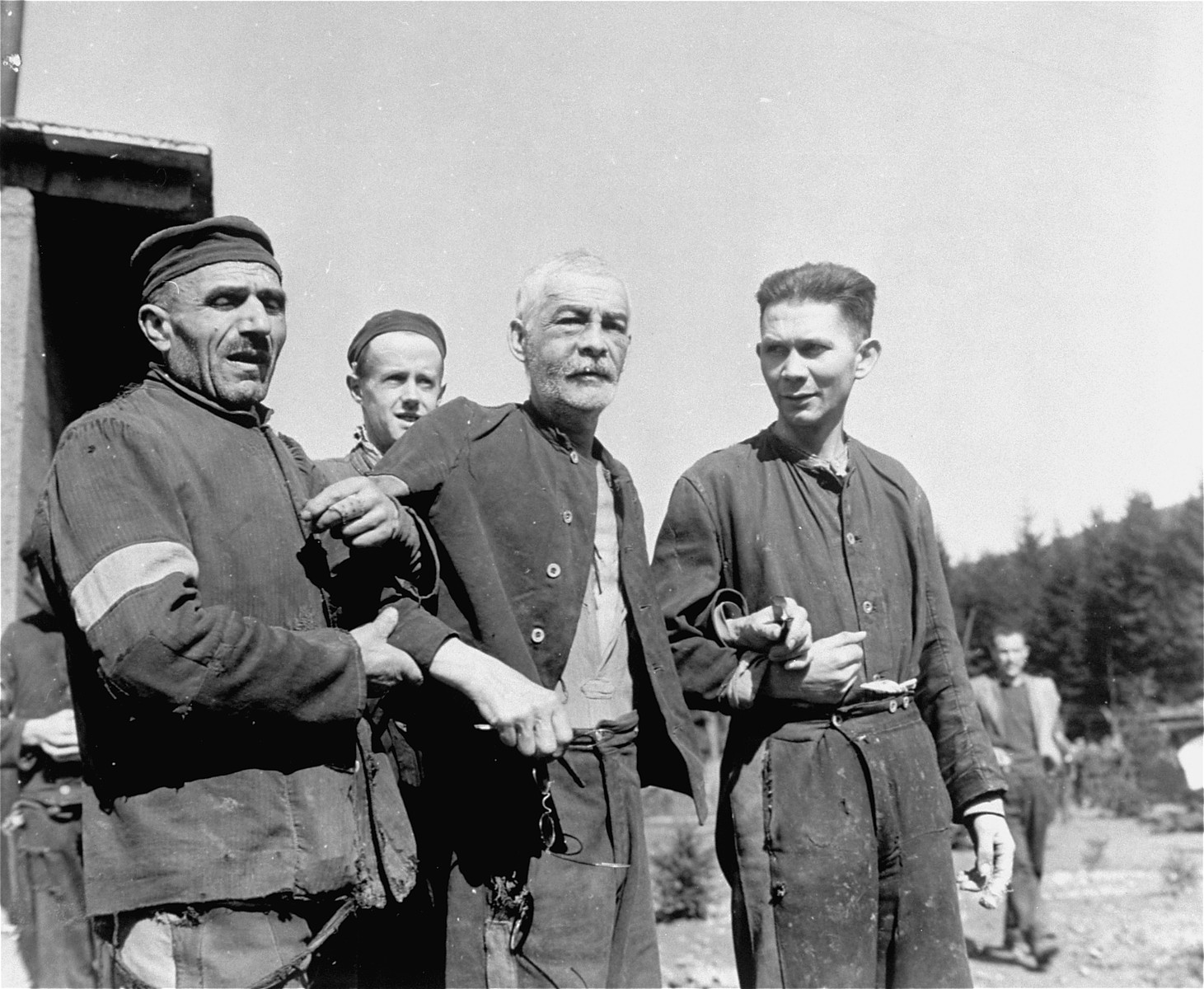 Two fellow prisoners support a weak and elderly Jewish man in the concentration camp at Holzen, Germany. These prisoners, subject to starvation, beatings, and disease, were liberated by units of the 9th U.S. Army.