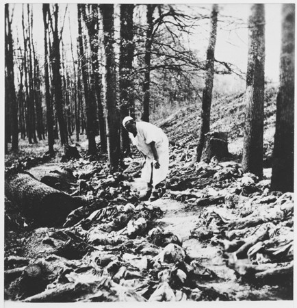 A Yugoslav war crimes investigator (named Rodic) examines exhumed bodies in the Uskoci Forest.