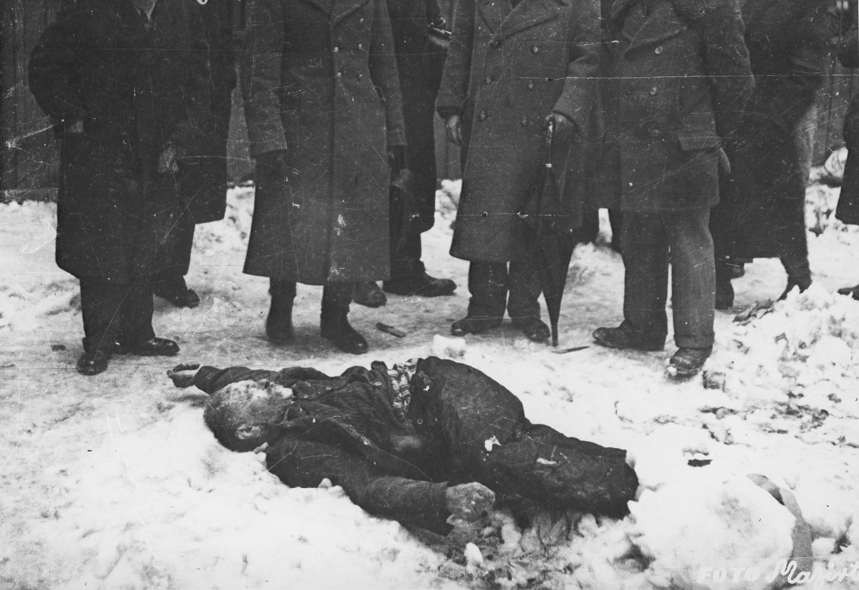 Members of the Commission for the Investigation of Nazi and Arrow Cross Atrocities examine the body of a Jewish man killed in the Budapest ghetto.

During the last few months of the war in Hungary, the Nyilas (Arrow Cross) exploited the anarchic conditions in the areas still under their control to continue their excesses against the Jews.  This was particularly true in Budapest, despite the fact that the Soviet army had completely encircled the city by December 27, 1944.  The reign of terror that had begun with Szalaszi's assumption of power on October 15, 1944, went almost completely unchecked after the beginning of the Soviet siege on December 9.  Gangs of armed Nyilas--mostly teenagers--roamed the city hunting for Jews in hiding.  They searched them out in hospitals, shelters, homes outside the ghetto, in the International Ghetto, and in the large ghetto.  After robbing the Jews of their remaining valuables, the Nyilas shot them on the spot or marched them to the banks of the Danube, where they shot them, and threw their bodies into the river.  A large number of Jews who were murdered in the ghetto were buried in mass graves in the courtyard of the Dohany Street Synagogue.

The most horrific of these attacks occurred on the Pest side of the capital, at the two Jewish hospitals located on Maros and Varosmajor streets.  The Maros Street hospital, which had operated under the protection of the International Red Cross during the German occupation, was attacked on January 11, 1945.  After the initial melee, during which Nyilas gang members wantonly destroyed hospital equipment, threw patients out of their beds and trampled them, and murdered staff members, survivors were ordered to dig a mass grave, remove and bury the bodies.  They were then shot and buried in the grave themselves.  Only one nurse survived of the 92 people that were in the hospital at the time.  Three days later, on January 14, the hospital on Varosmajor Street was attacked, resulting in the deaths of 150 patients and medical staff.  These manhunts and massacres continued unabated until the liberation of Budapest in April.  [R. Braham, "The Politics of Genocide," vol. 2: 995-1007]