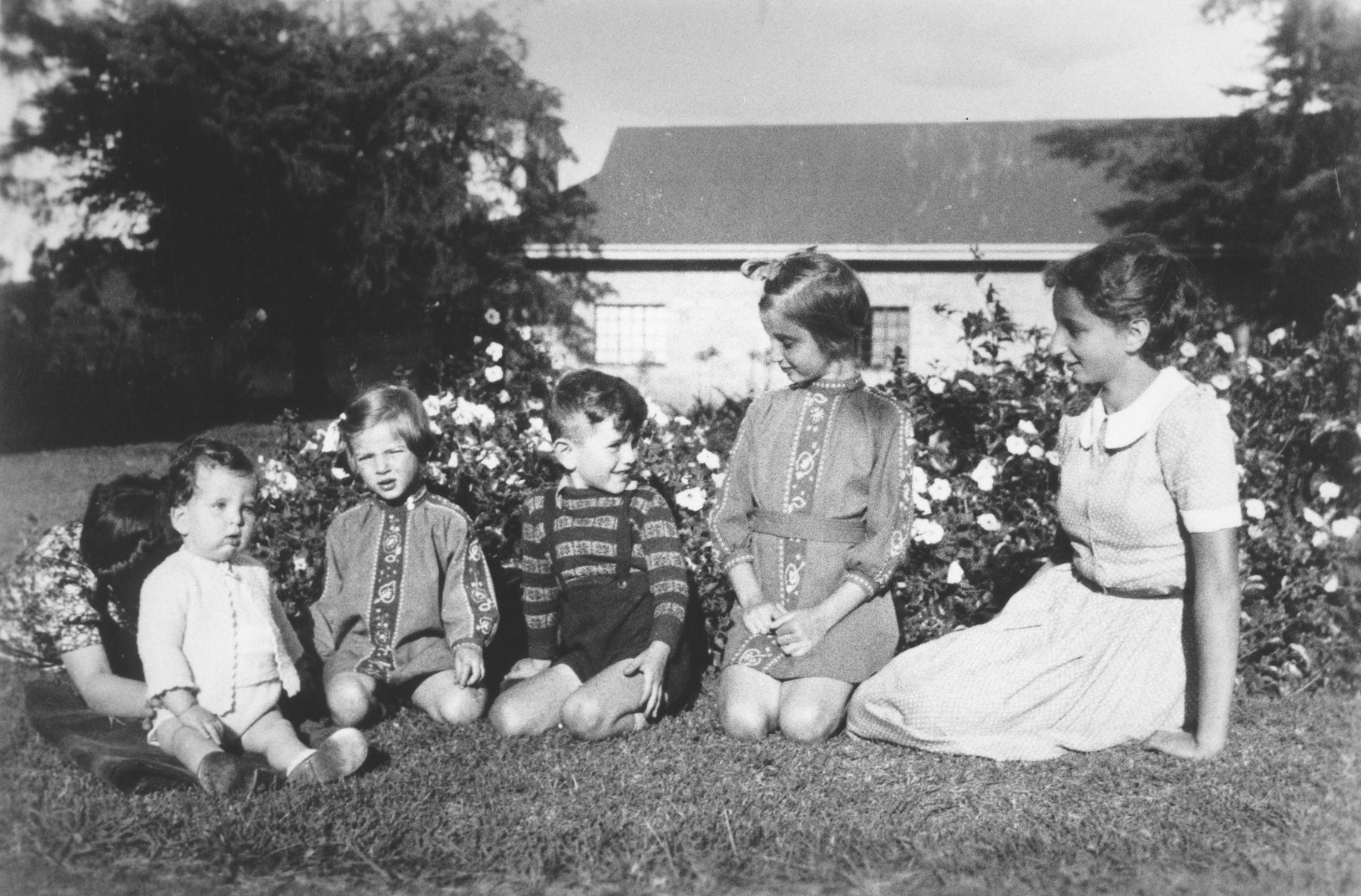 Five Jewish refugee children pose outside on the lawn of their farm near Limuru, Kenya (Kiambu district), where they found refuge during World War II.

Pictured from left to right are Philip Berg (being supported by his Aunt Erna), Hannah Baum, Egon, Gisela and Inge Berg.