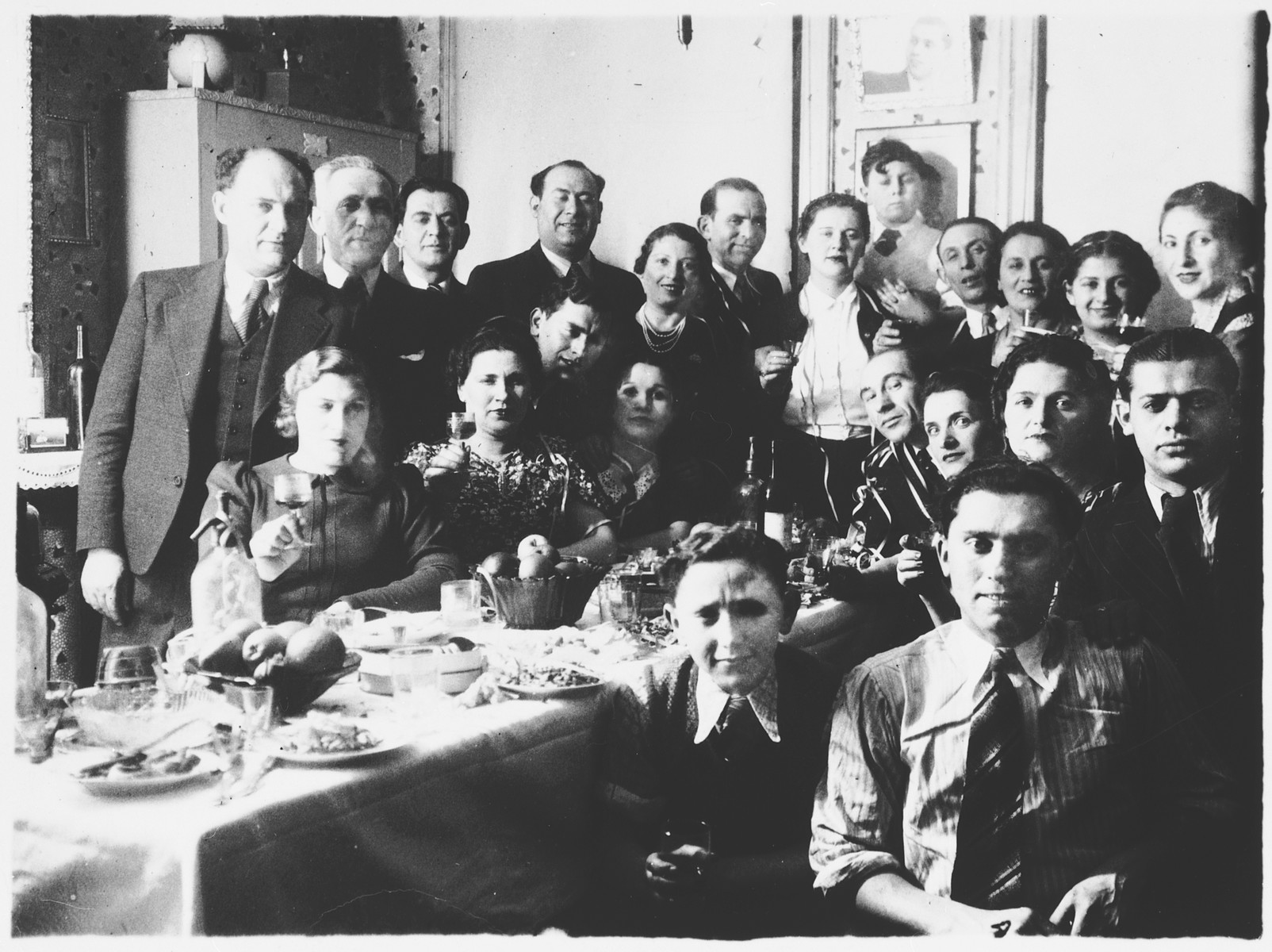 Group portrait of family and friends who have gathered to celebrate the Aufruf (pre-wedding ceremony) of Leah Mendelowicz and Alex Ciechanow.

Among those pictured are Alex Ciechanow (at the bottom right), Leah Mendelowicz (second row from the front, third from the right), and Fani Mendelowicz (second row from the front, second from the right).