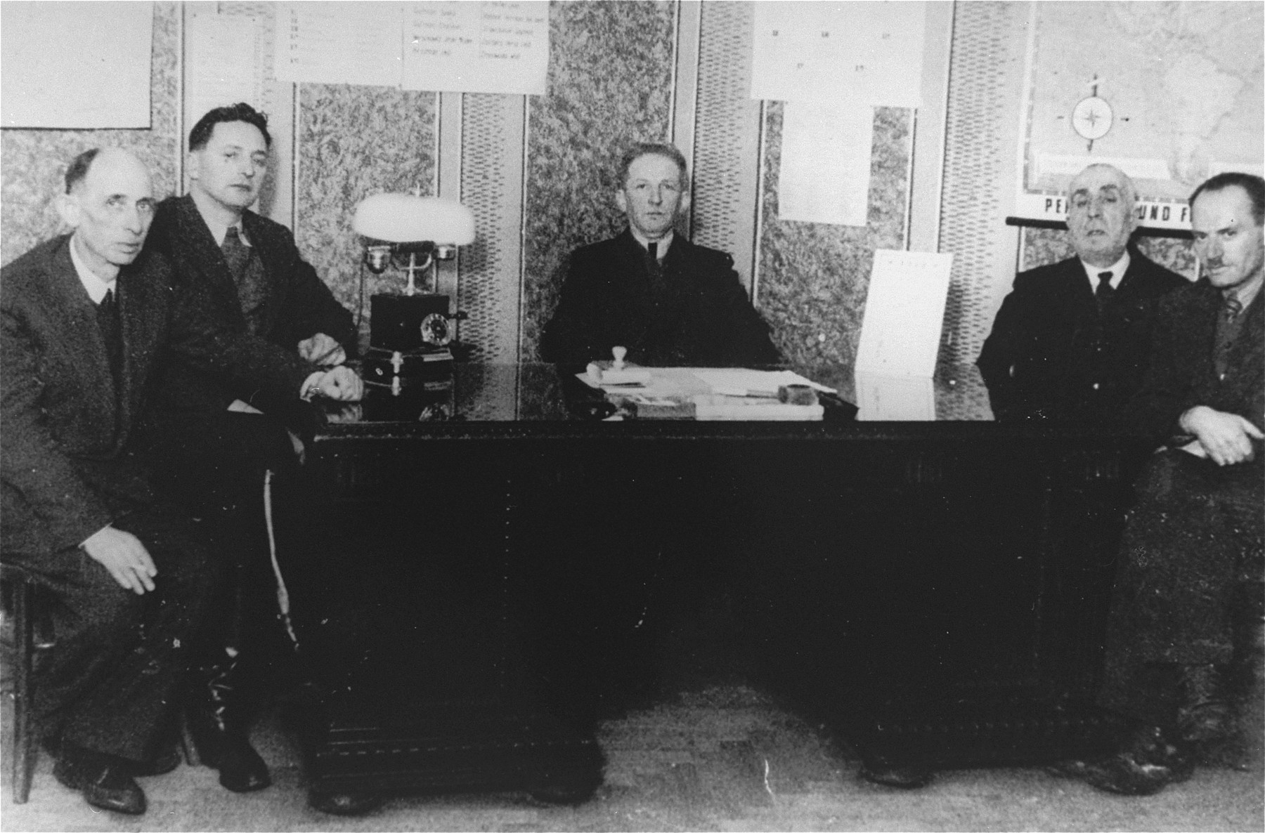Members of the ghetto administration pose around a desk in the office of the Judenrat in the Kielce ghetto.

This photo was one the images included in an official album prepared by the Judenrat of the Kielce ghetto in 1942.
