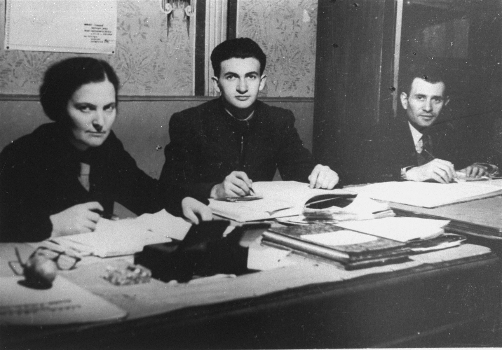 Three members of the administrative staff of the Kielce ghetto Judenrat (Jewish Council) at work in their office.

This photo was one the images included in an official album prepared by the Judenrat of the Kielce ghetto in 1942.