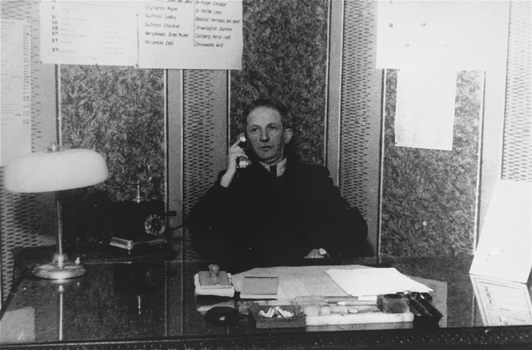 A member of the ghetto administration talks on the telephone while seated at his desk in the office of the Judenrat in the Kielce ghetto.

This photo was one the images included in an official album prepared by the Judenrat of the Kielce ghetto in 1942.