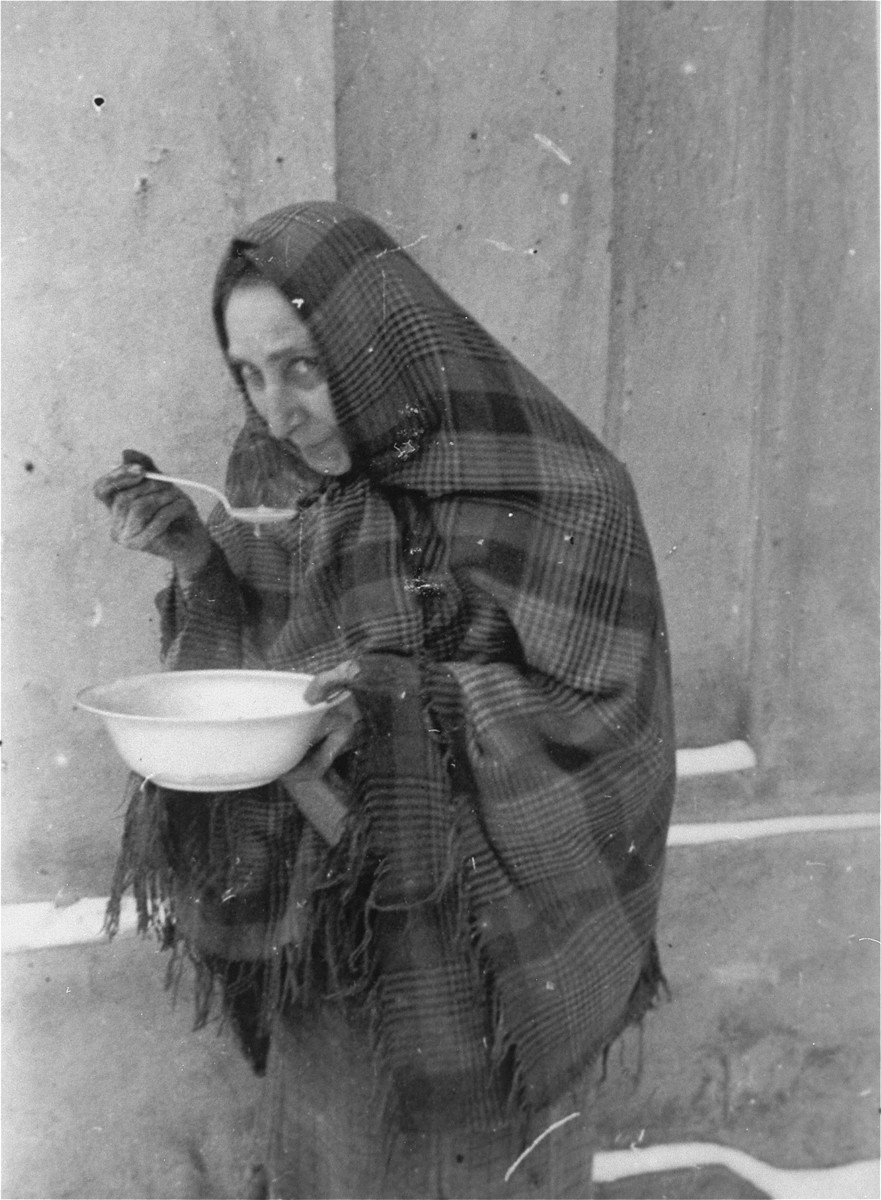 A Jewish woman eats a bowl of soup that she received at the public kitchen in the Kielce ghetto.  

This photo was one the images included in an official album prepared by the Judenrat of the Kielce ghetto in 1942.