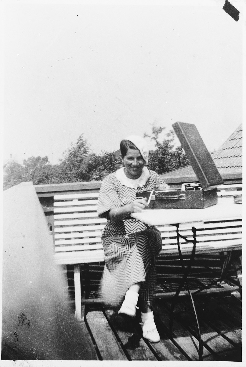 A young Jewish woman poses with a phonograph while on vacation on the Oresund in Faxe Ladeplads, Denmart,

Pictured is Kaja Diament.