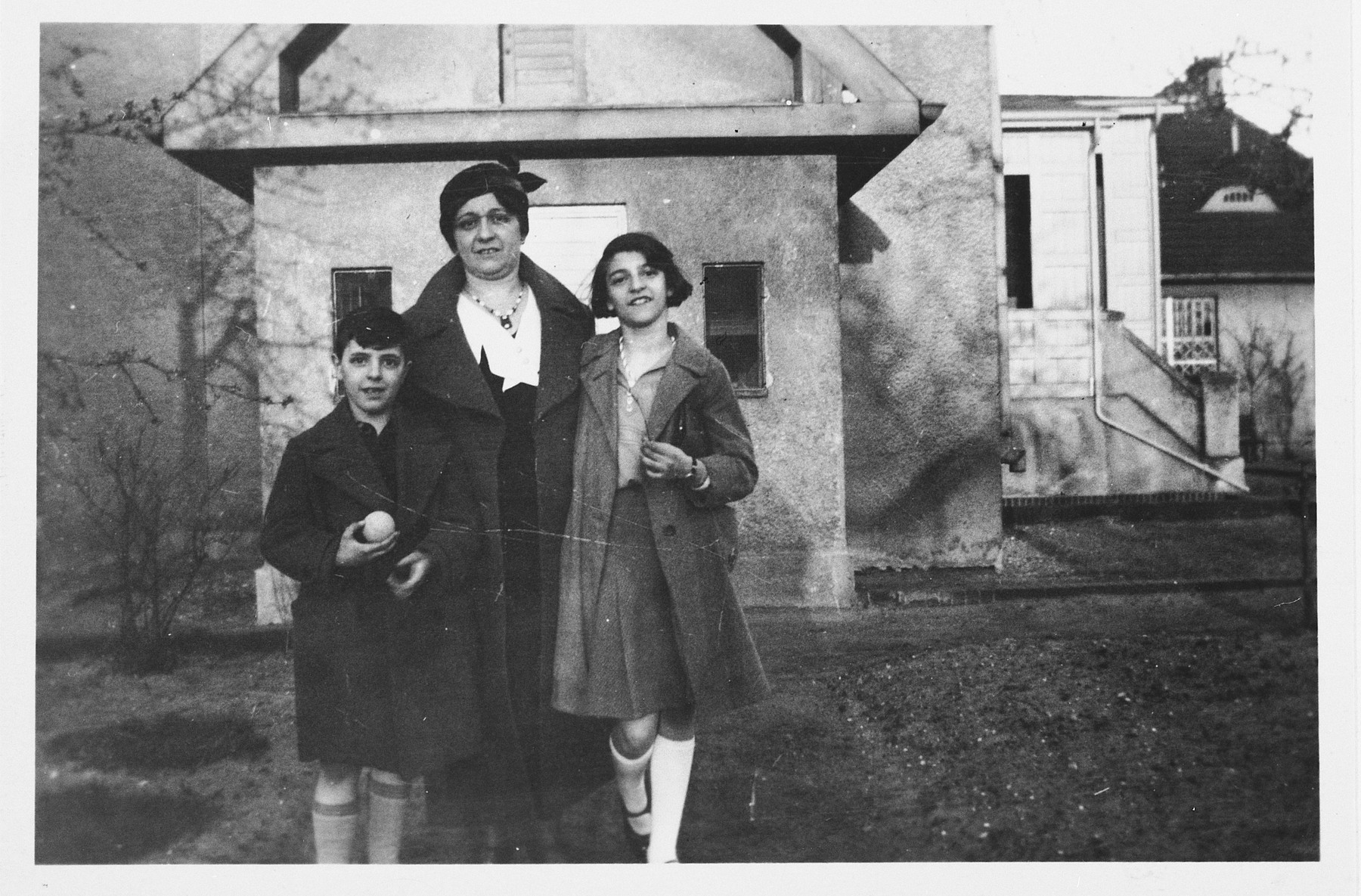 A Jewish mother and her two children pose outside an old age home in Germany.

Pictured from left to right are: Heinz, Ella and Alice Redlich.