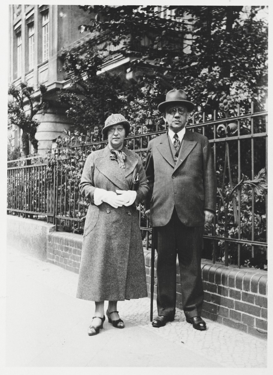 Louis and Margarethe Wilhelm pose on a sidewalk next to a rod iron fence.  

Louis and Margarethe Wilhelm were the parents of Annie Witting.  Louis Wilhelm was a wholesale wheat merchant with a seat on the Wheat Exchange in Berlin.  He died of natural causes on March 23, 1941.  After his death, Margarethe went into hiding.  She eventually committed suicide on November 15, 1943 at the age of 61.