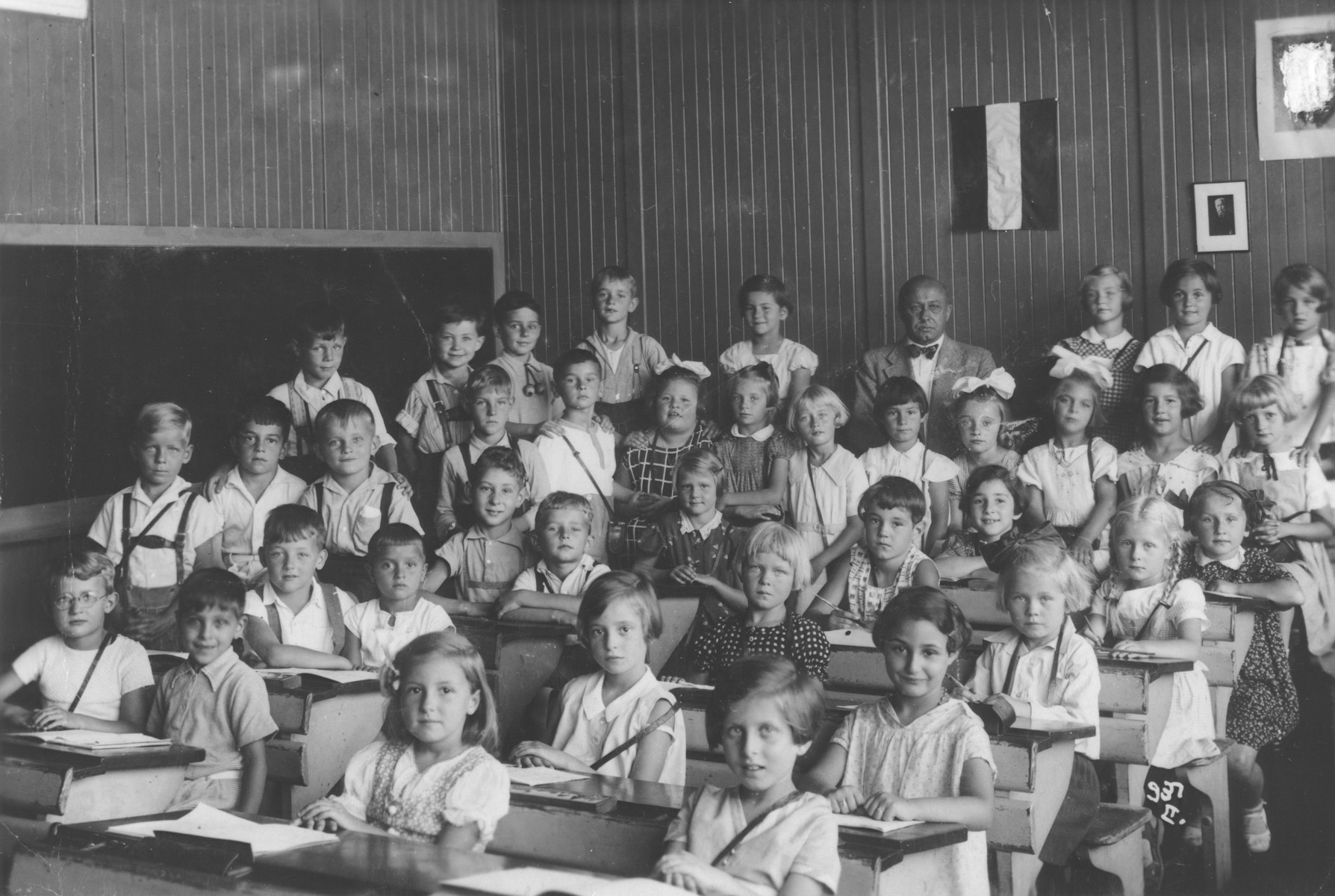 Children sit at their desks in a school in the Templehof neighborhood of Berlin.

Among those pictured is Paul Oppenheimer (third row, second from the left), the only Jewish child in the school.  A portrait of Hitler hanging on the wall was later rubbed out by the donor.