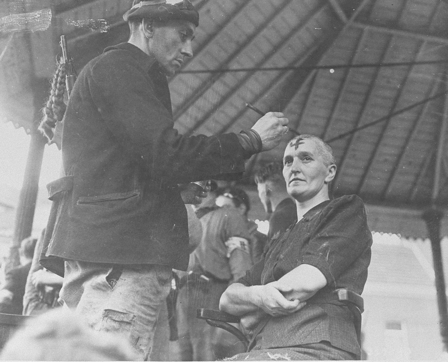 A member of the Belgian resistance paints a swastika on the forehead of a woman who collaborated with the Germans during the occupation of Belgium.  The resistance shaved her head and the heads of four other women in Lanaken as part of their public humilation.