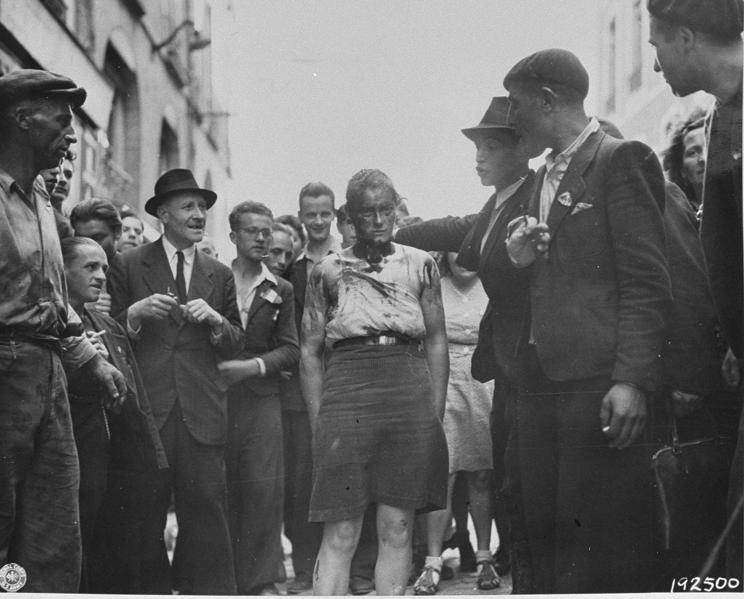 Civilians and members of the French resistance lead a female collaborator through the streets of Rennes after her head was shaven and covered with iodine.