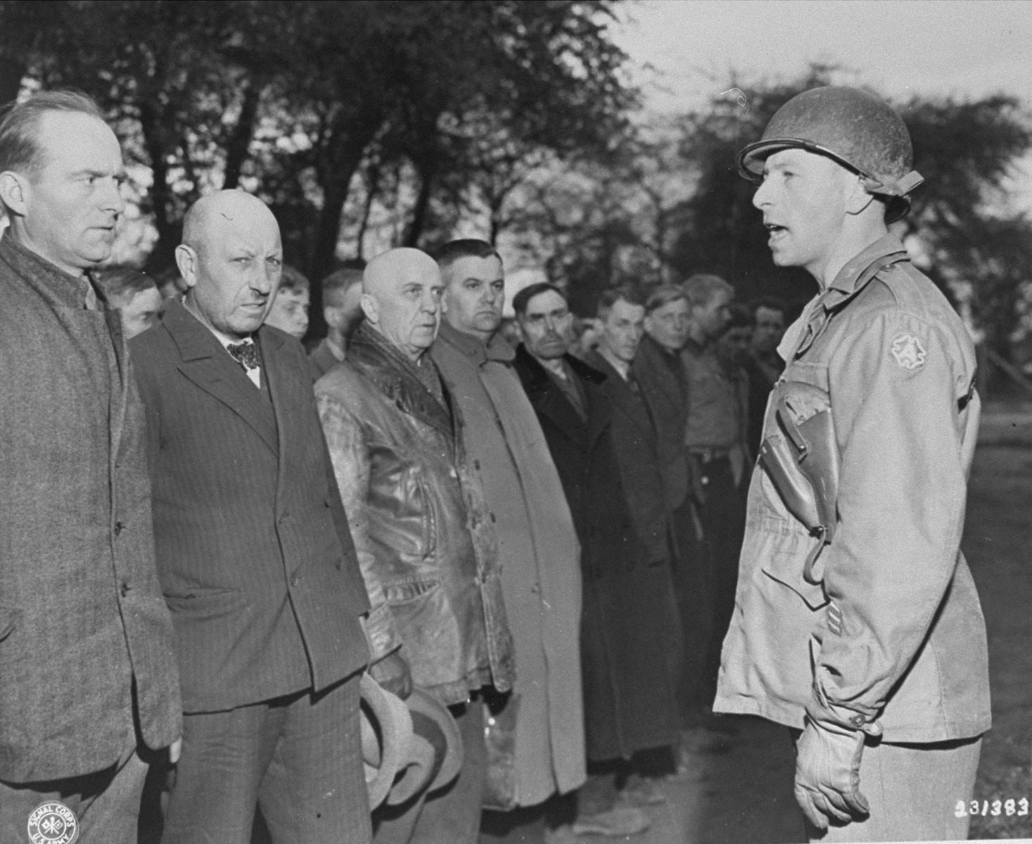 An American officer speaks to new German prisoners upon their arrival at the Recklinghausen internment camp, which was established by the U.S. Ninth Army.

When U.S. Ninth Army troops captured the concentration camp for Soviet civilians located near Recklinghausen, Germany, they converted it into a separation center for prisoners of war and war criminals.  After the first German prisoners arrived at the camp they were sent to the interrogation department, which was supervised by Captain Harold Puttfer and Lieutenant H. Goodman.  The camp had three sections called "cages."  One of these was for women, another for persons incarcerated for minor offenses, and the third for hardened criminals.  All three sections were filled to capacity, totalling 20,000 prisoners.