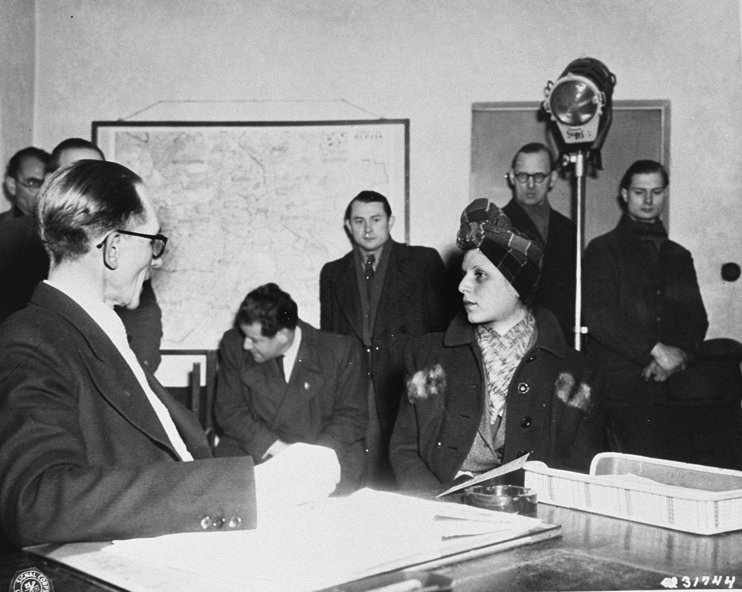 Criminal Commissar Jean Blome questions Stella Kubler (alias Issakson) about her wartime activities in Berlin denouncing Jews to the Gestapo.  

According to the Berlin prasidium court, Kubler informed on 2000 Jews while living in the city with her companion Rolf Isaakson.  The persons standing in the background are witnesses from the Jewish community of Berlin.