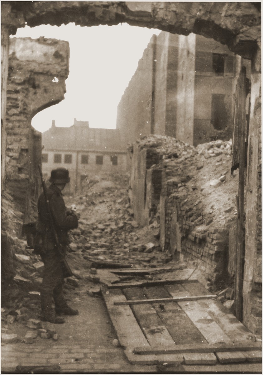 An SS soldier stands among ruins in the Warsaw ghetto during the suppression of the uprising.