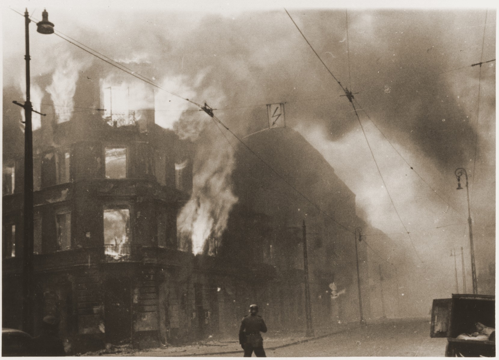 A housing block burns during the suppression of the Warsaw ghetto uprising.  

The original caption (translated from German) reads: "Destruction of a housing block."