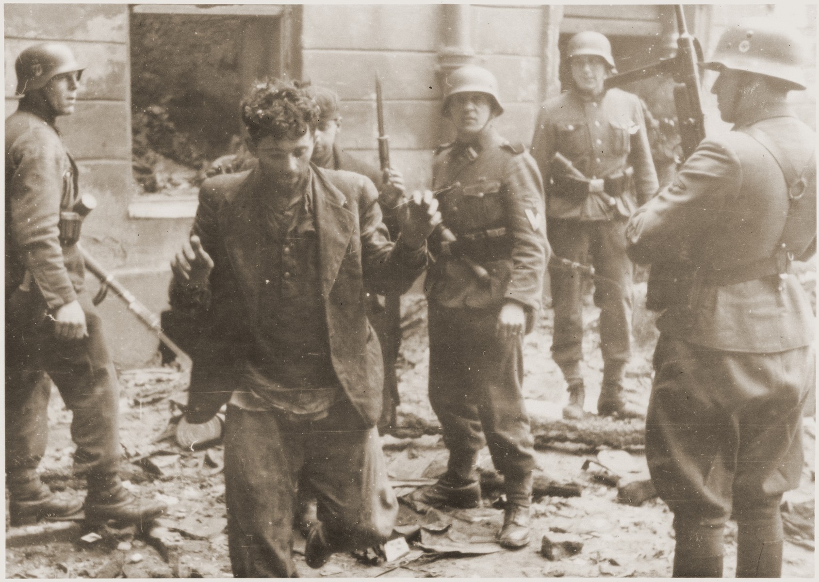 SS assault troops capture two Jewish resistance fighters pulled from a bunker during the suppression of the Warsaw ghetto uprising.  

The original caption (translated from German reads alternately: "Pulled from a bunker" or "Bandits."