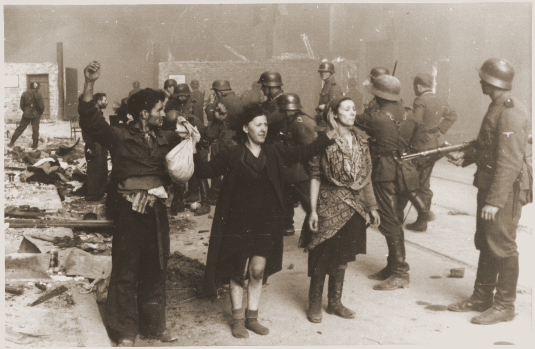 SS troops guard members of the Jewish resistance captured during the suppression of the Warsaw ghetto uprising.  The original German caption reads: "These bandits offered armed resistance."