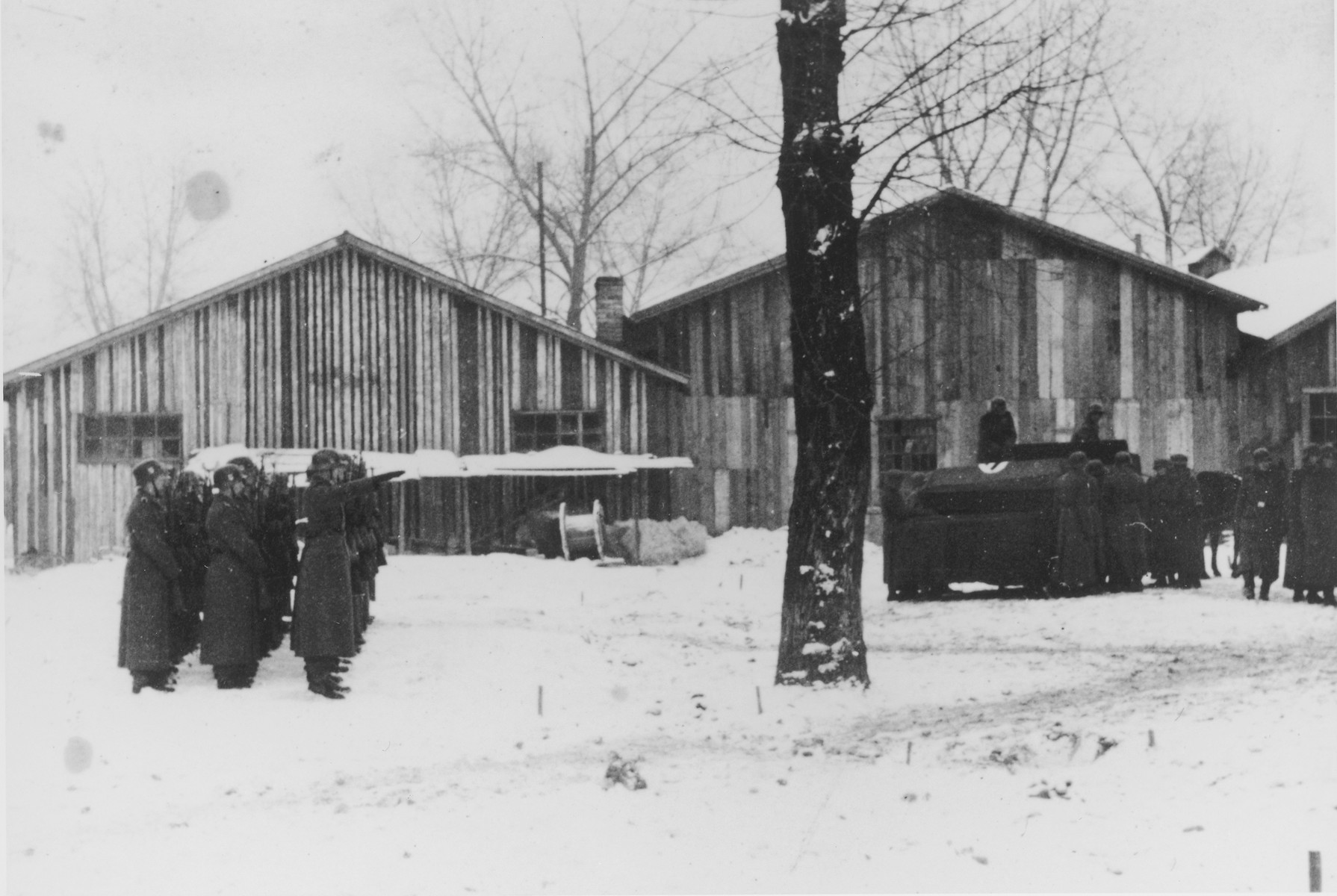 Three rows of German soldiers stand at attention and salute during a military funeral in Auschwitz.

The original caption reads "Beisetzung von SS Kameraden nach einem Terrorangriff."  (Burying our SS comrades from a terror attack.)

[This probably is the aftermath of the December 26 bombing based on the snow on the ground but it could also be September 13th bombing of IG Farben in which 15 SS men died in the SS residential blocks and 28 were seriously wounded.]