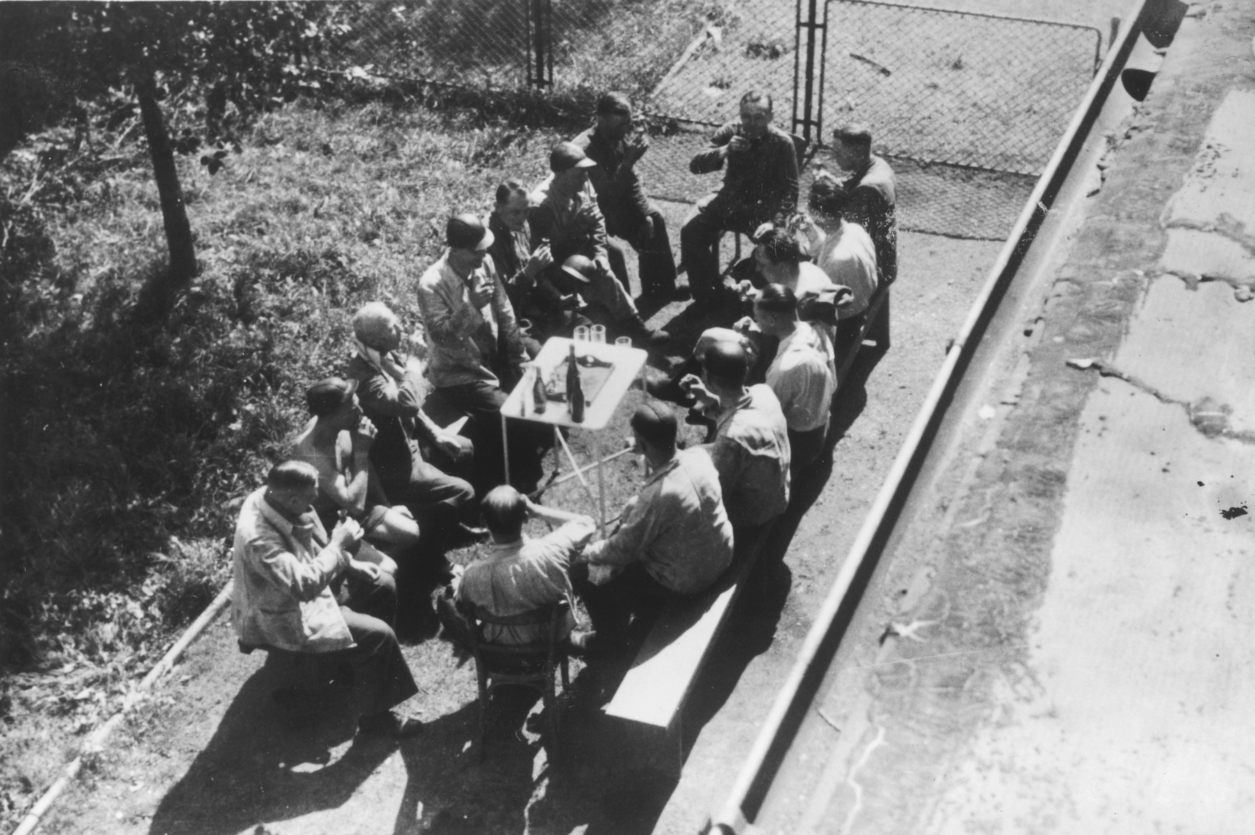 Auschwitz personnel, including many physicians, enjoy drinks at an outdoor table drinking following a visit to a coal mine.

The original caption reads "Nach der Ausfahrt" (after the outing [exiting the mine]).