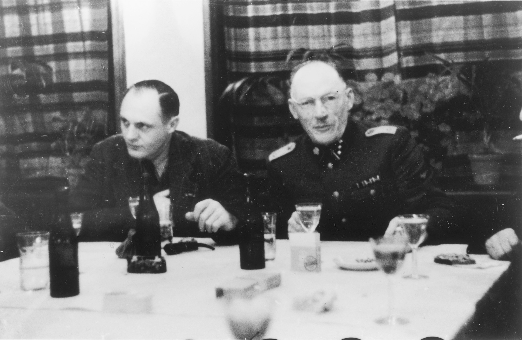 Two SS officers gather for drinks in a hunting lodge.

From left to right are Dr. Eduard Wirths and Heinrich Josten.