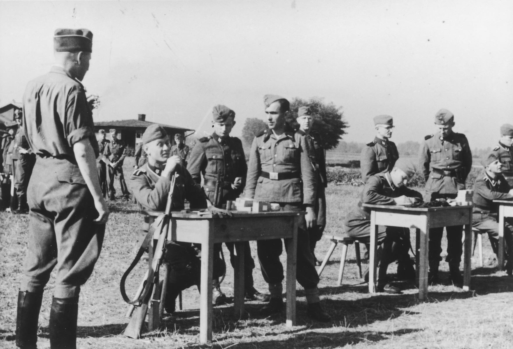 SS officers gather for shooting practice. On the far left is Karl Hoecker(with his back to camera).

The original caption reads "Auf dem Schiessstand" (at the firing range).