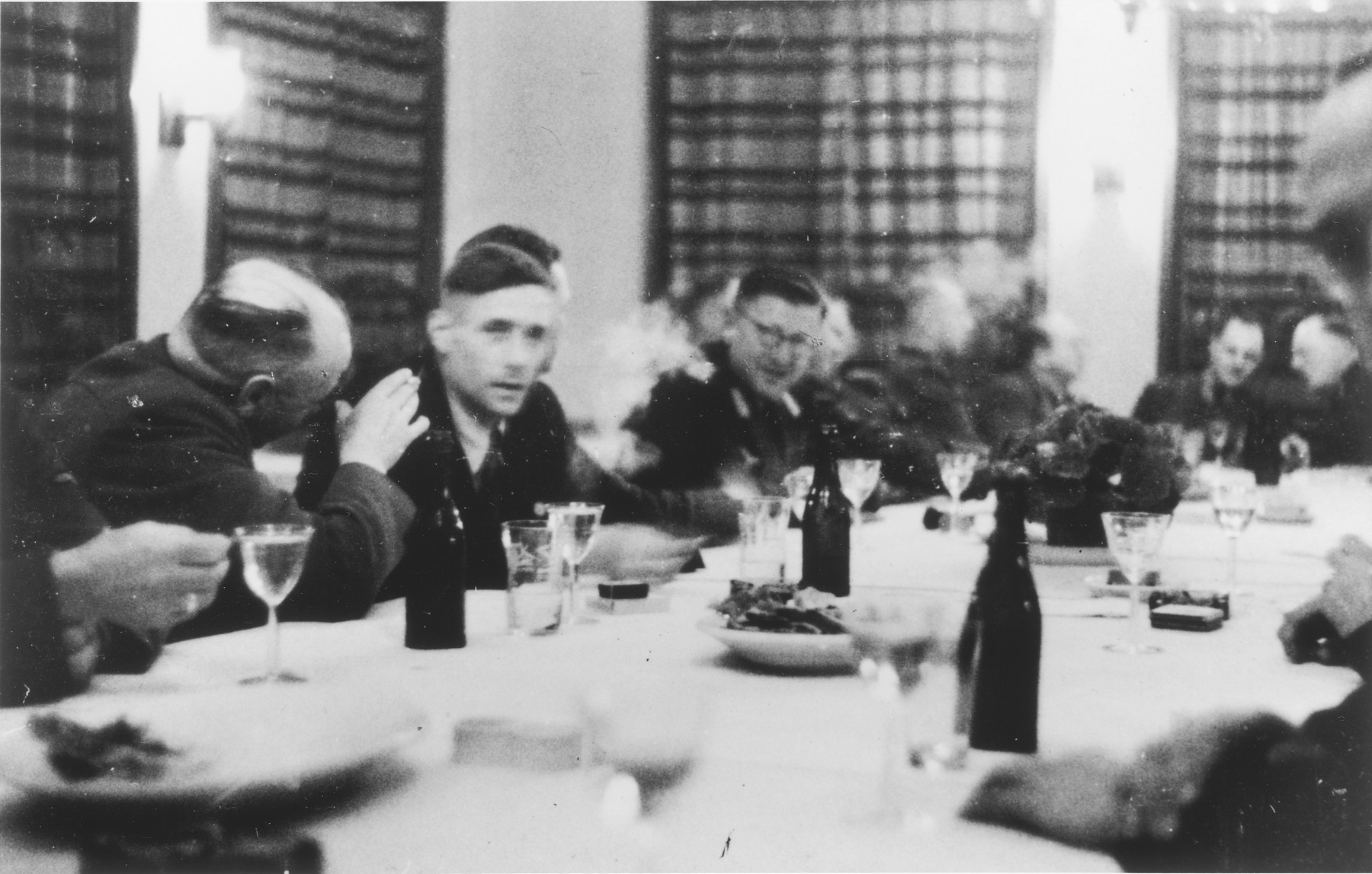 SS officers gather for drinks in a hunting lodge.

Among those pictured is Heinrich Josten (head of the table, right).