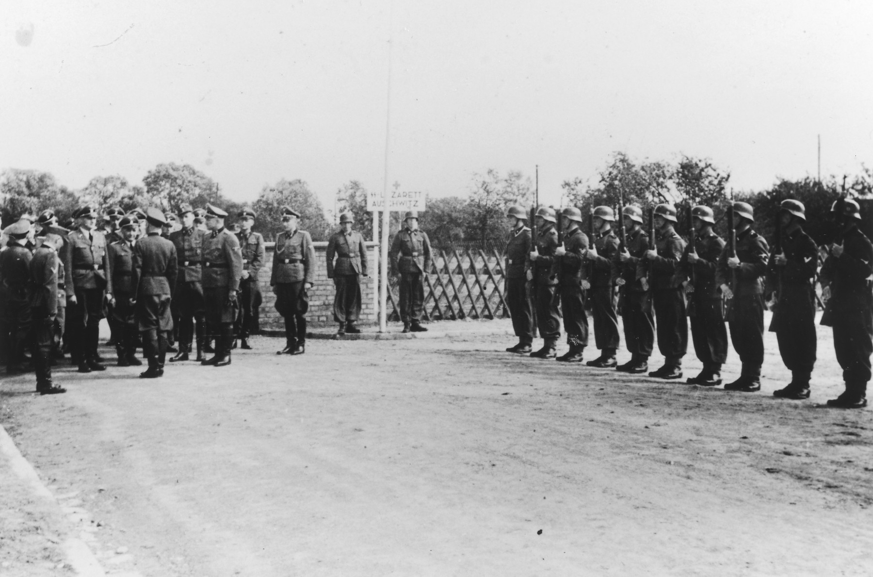 Dedication of the new SS hospital in Auschwitz. 

The original caption reads "Die Ubergabe" (the handover).  The ceremony marks the transfer of documents and authority from the construction department to the camp upon completion of the project.