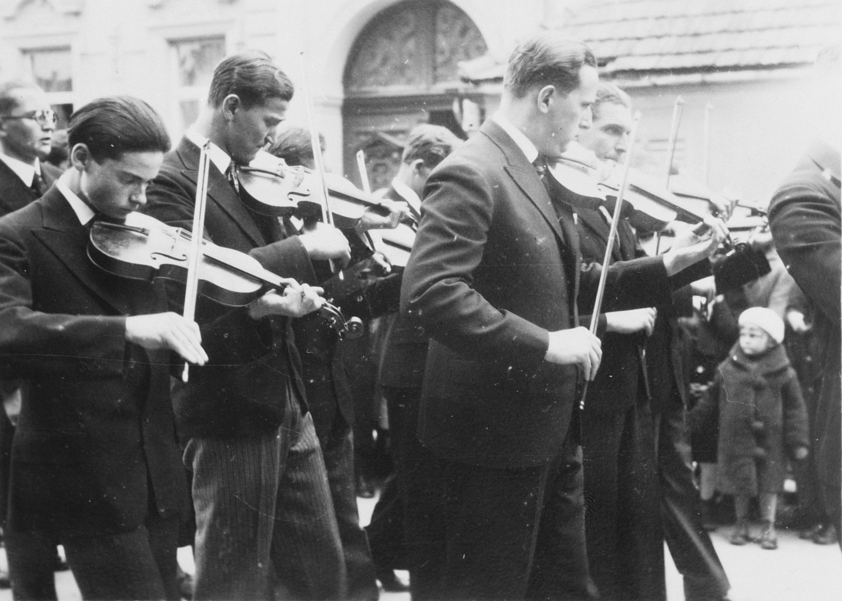 Graduates of a Gymnasium in Budapest parade to the commencement excercises playing the violin.

Among those pictured is Denes Simonyi (left), one of three Jewish students.