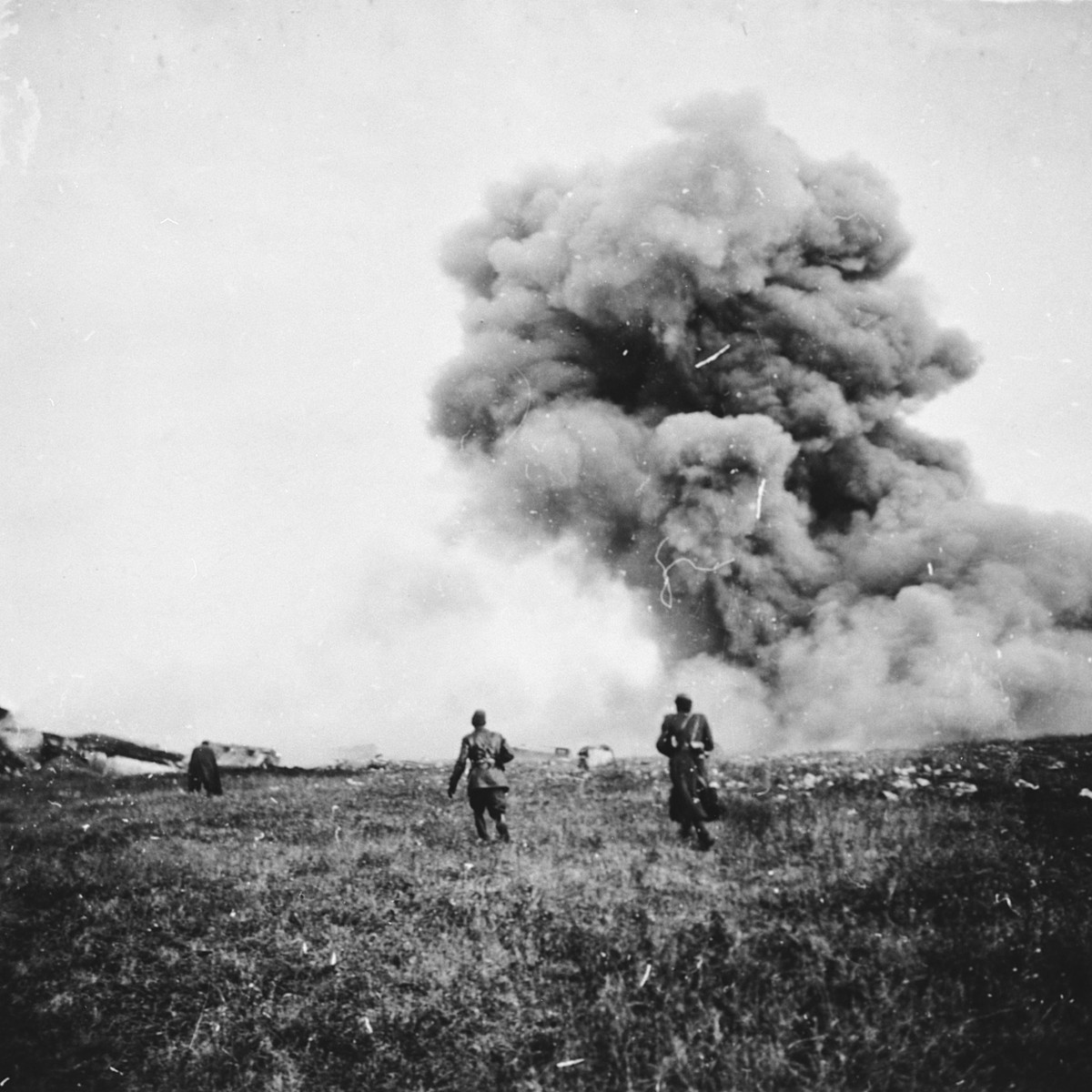 Members of a Hungarian forced labor battalion run from an explosion [in Oradea] where they are accompanying the Hungarian army's advance into Transylvania.

The original caption reads, "After the explosion, a cloud of smoke."