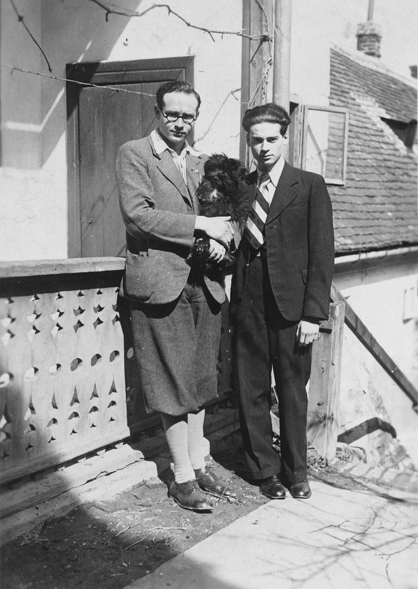 Two Hungarian Jewish brothers pose outside their home holding their pet dog, "Puli."

Pictured are Bandi and Denes Simonyi.