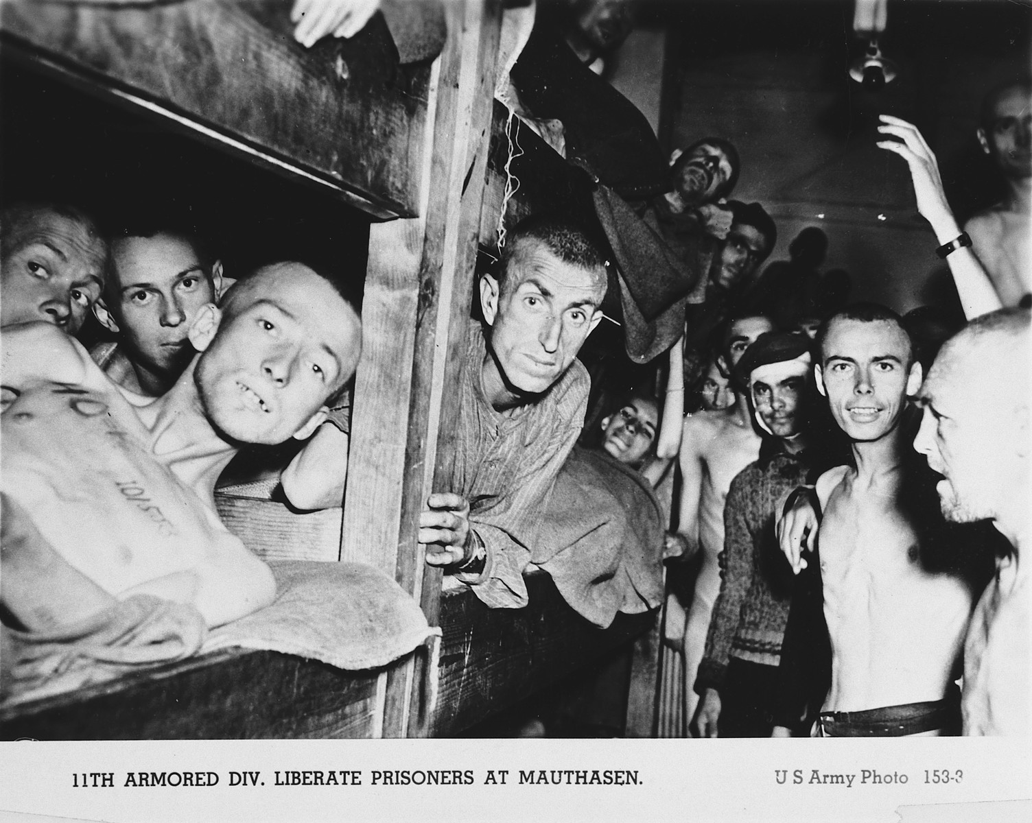 Prisoners liberated from Mauthausen, many crowded into a wooden bunk, celebrate their liberation by the American 11th Armored Division.

The man pictured second from the left has been identified as Ferencz Otto Braun.
